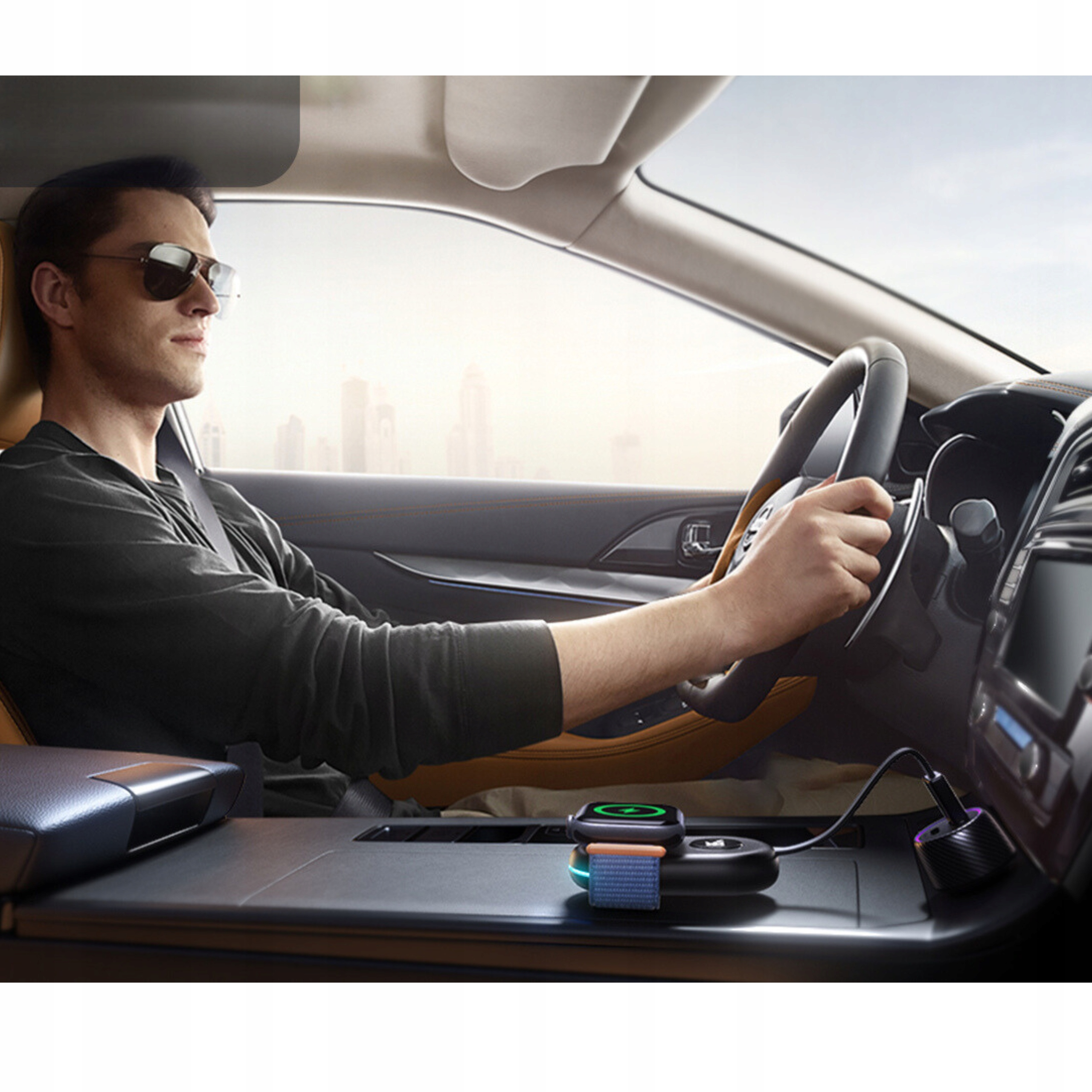 Mężczyzna prowadzący samochód, widoczna stacja ładowania bezprzewodowego z telefonem i zegarkiem.