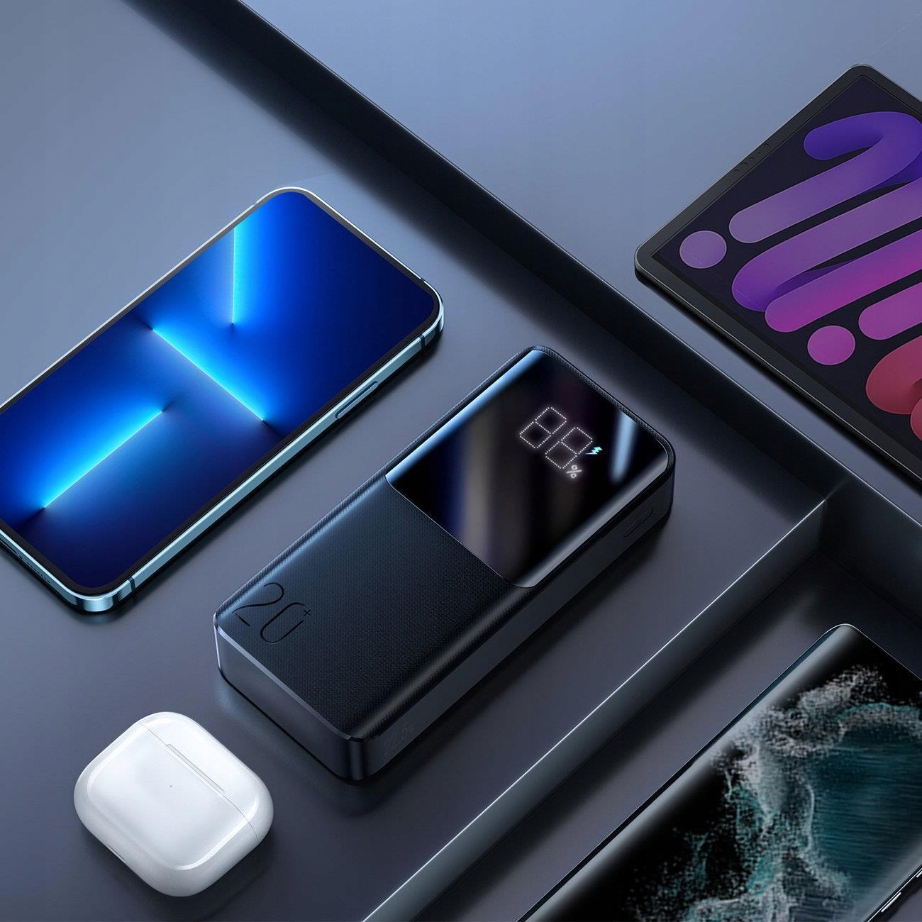 Power bank z telefonem, tabletem i słuchawkami na czarnej powierzchni.