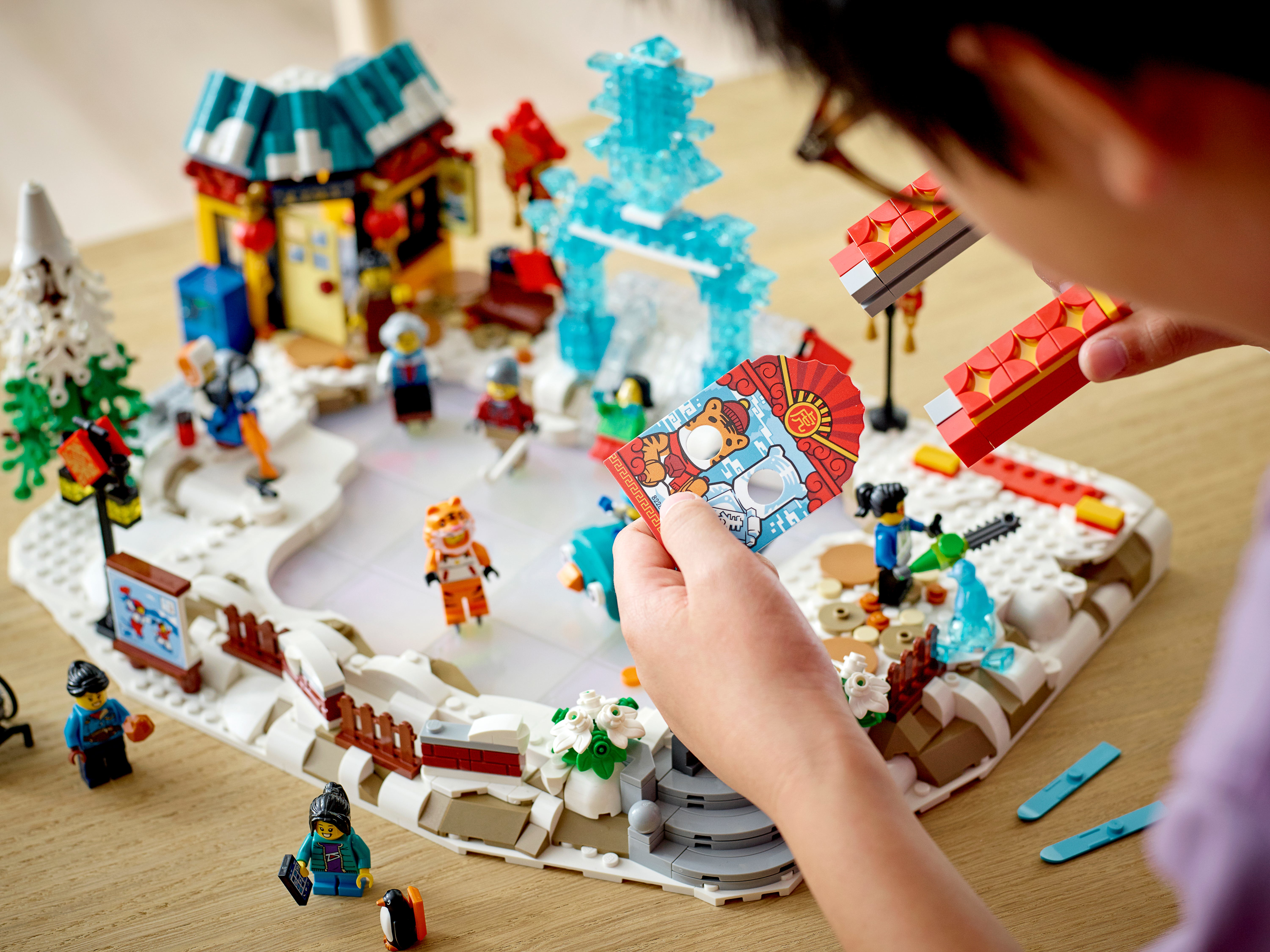 Un bambino gioca con un set LEGO del festival invernale. Focus sulle mani del bambino che tengono elementi LEGO.