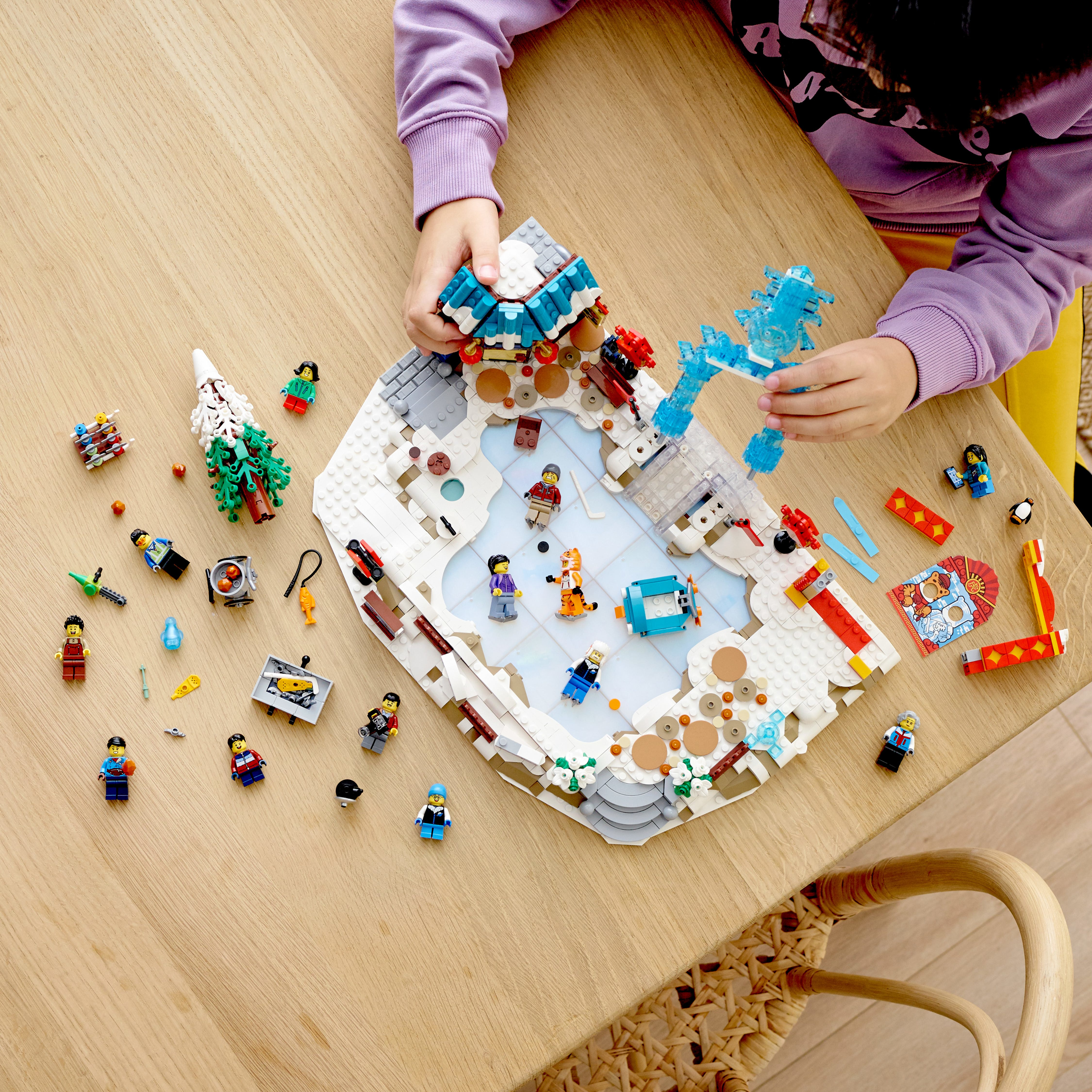 Vista dall'alto di un bambino che gioca con un set Lego su un tavolo di legno.