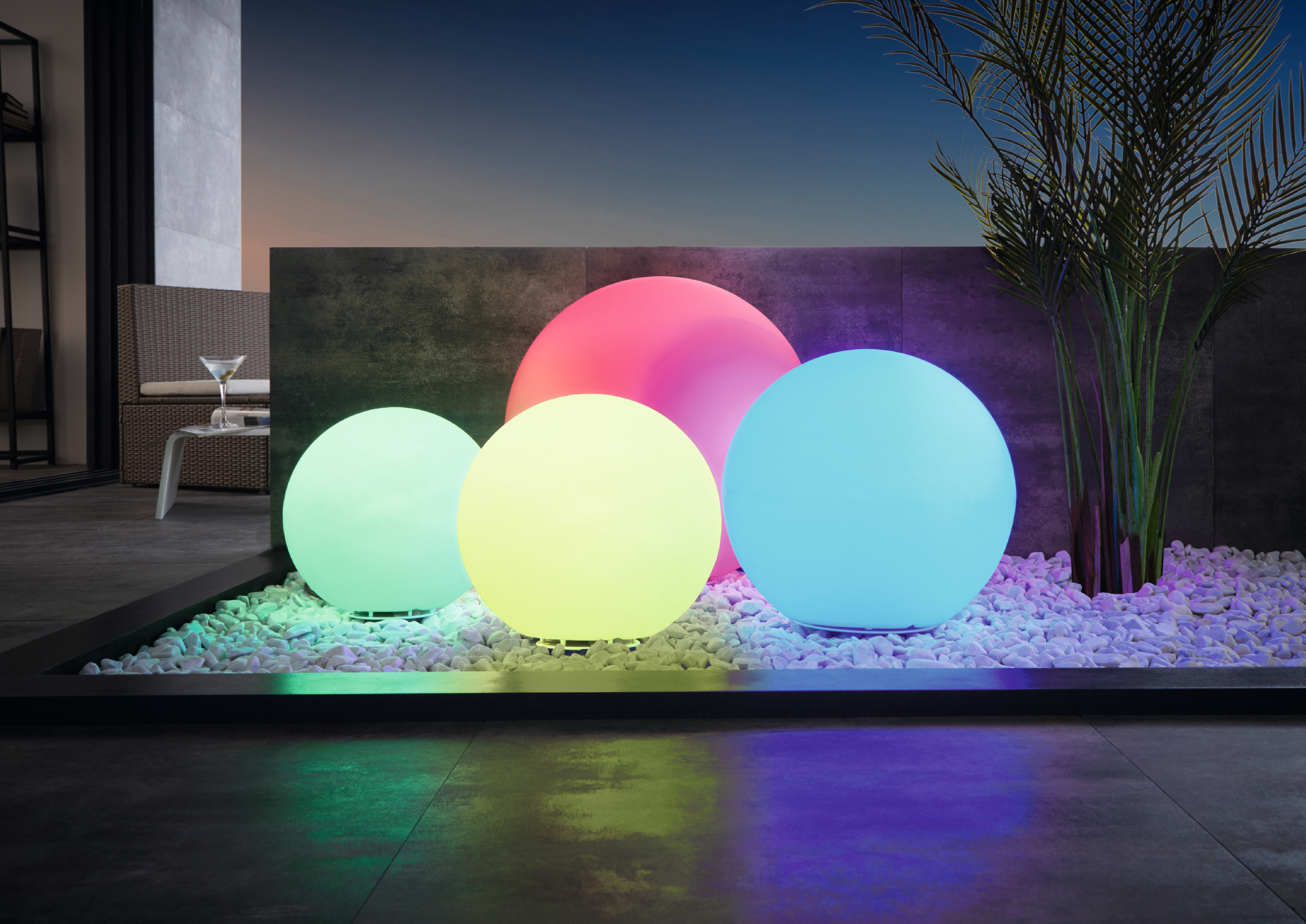 Scena all'aperto con quattro luci sferiche luminose in bianco, giallo, rosa e blu.