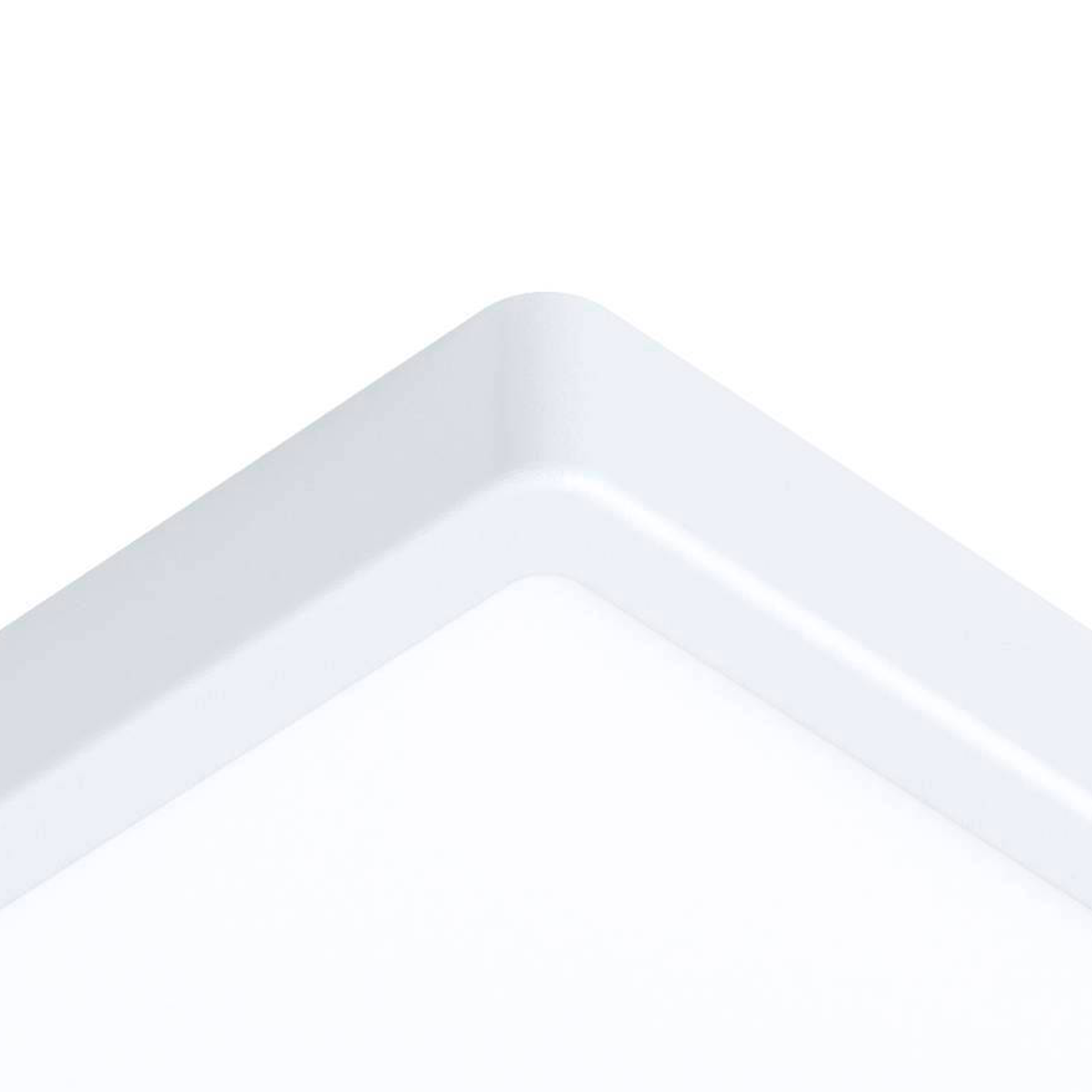 Primer plano de la esquina de una luz de techo LED cuadrada blanca contra un fondo blanco.
