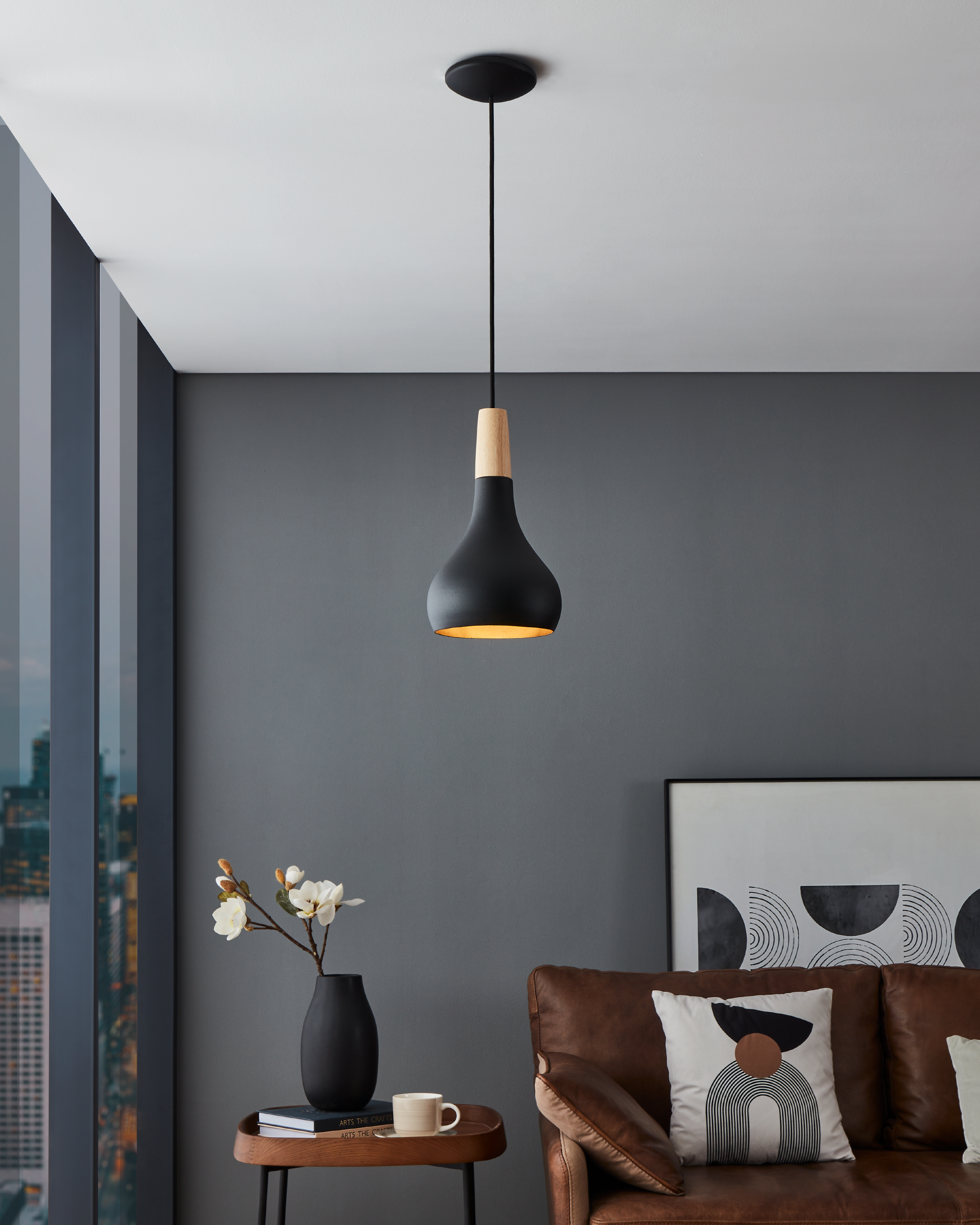 Una lampada a sospensione nera con accenti in legno è appesa in un soggiorno.