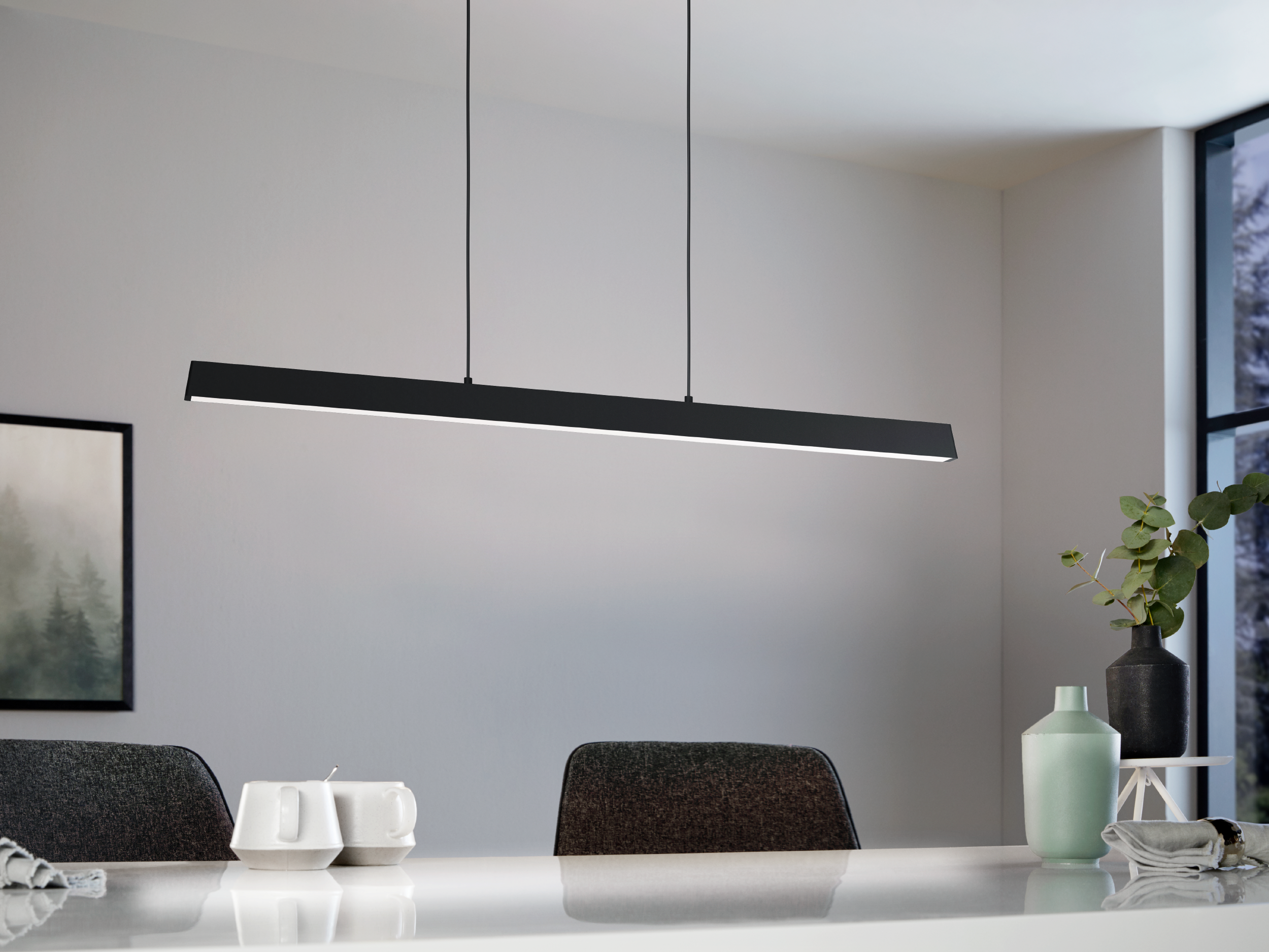 Eine moderne, schwarze lineare Pendelleuchte hängt über einem Tisch mit Stühlen und schafft einen eleganten Essbereich.