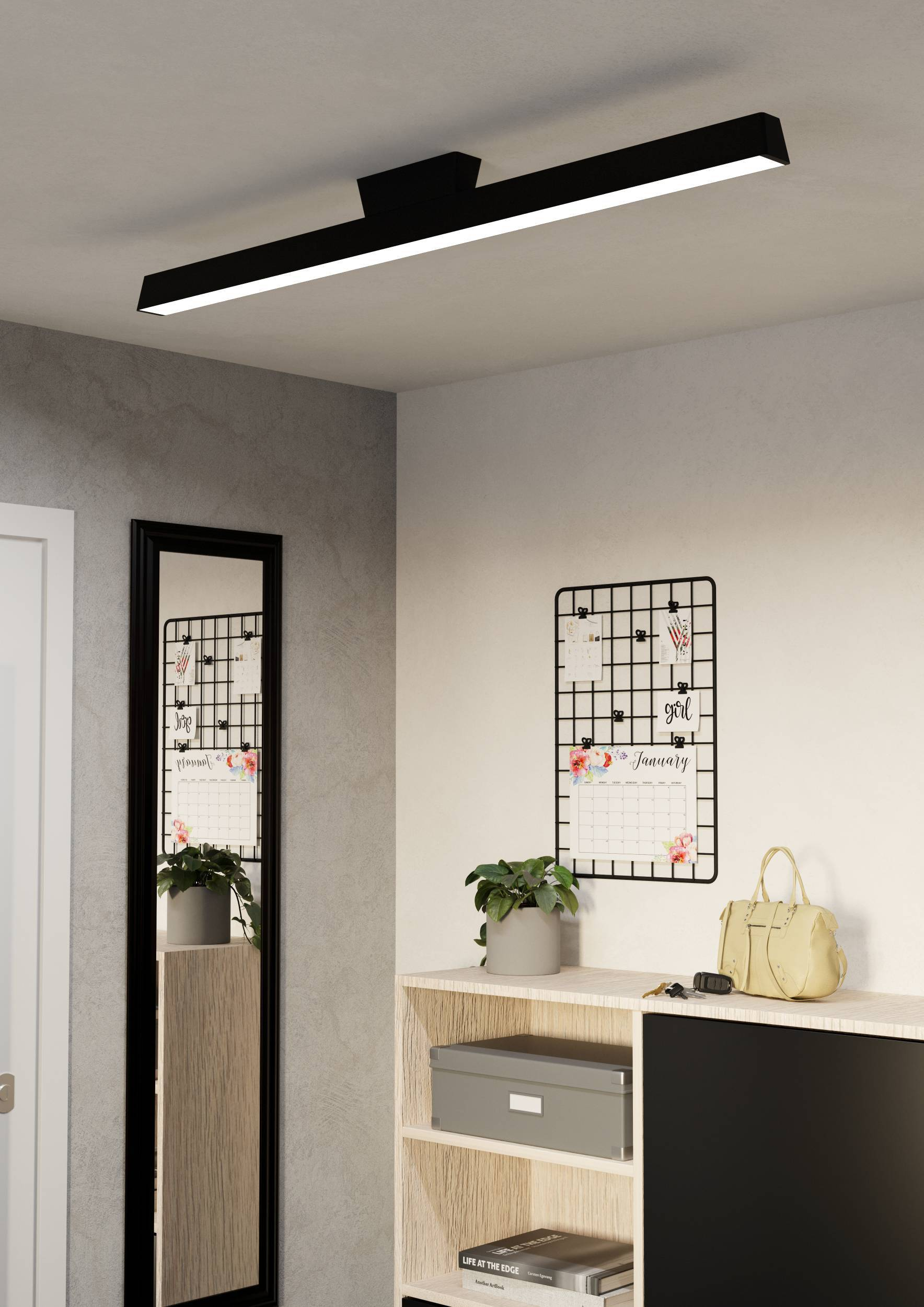 Una lampada da soffitto lunga e sottile con cornice nera e pannello luminoso bianco è montata a soffitto in una stanza.