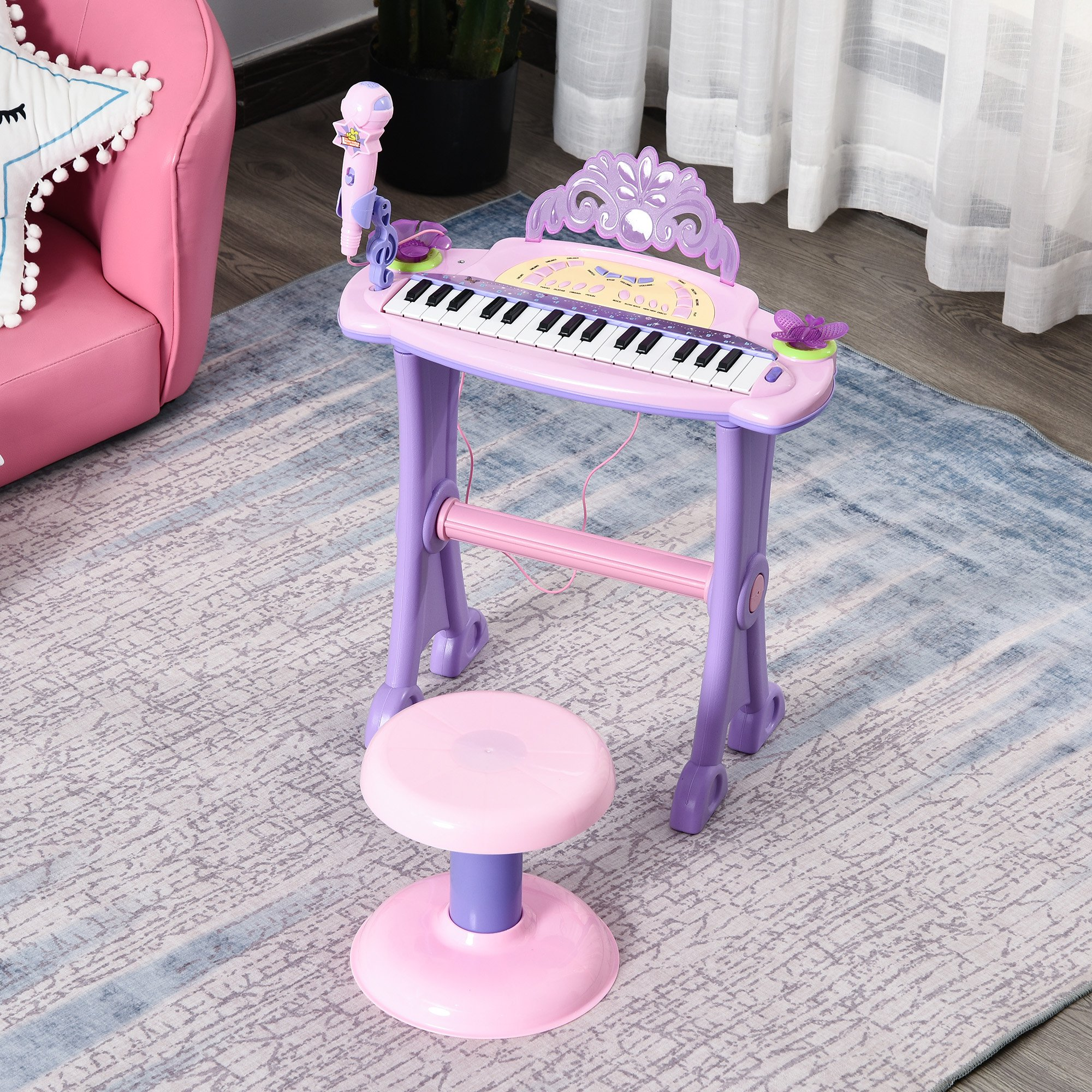 Un piano de juguete rosa y morado con un taburete y un micrófono sobre una alfombra estampada.