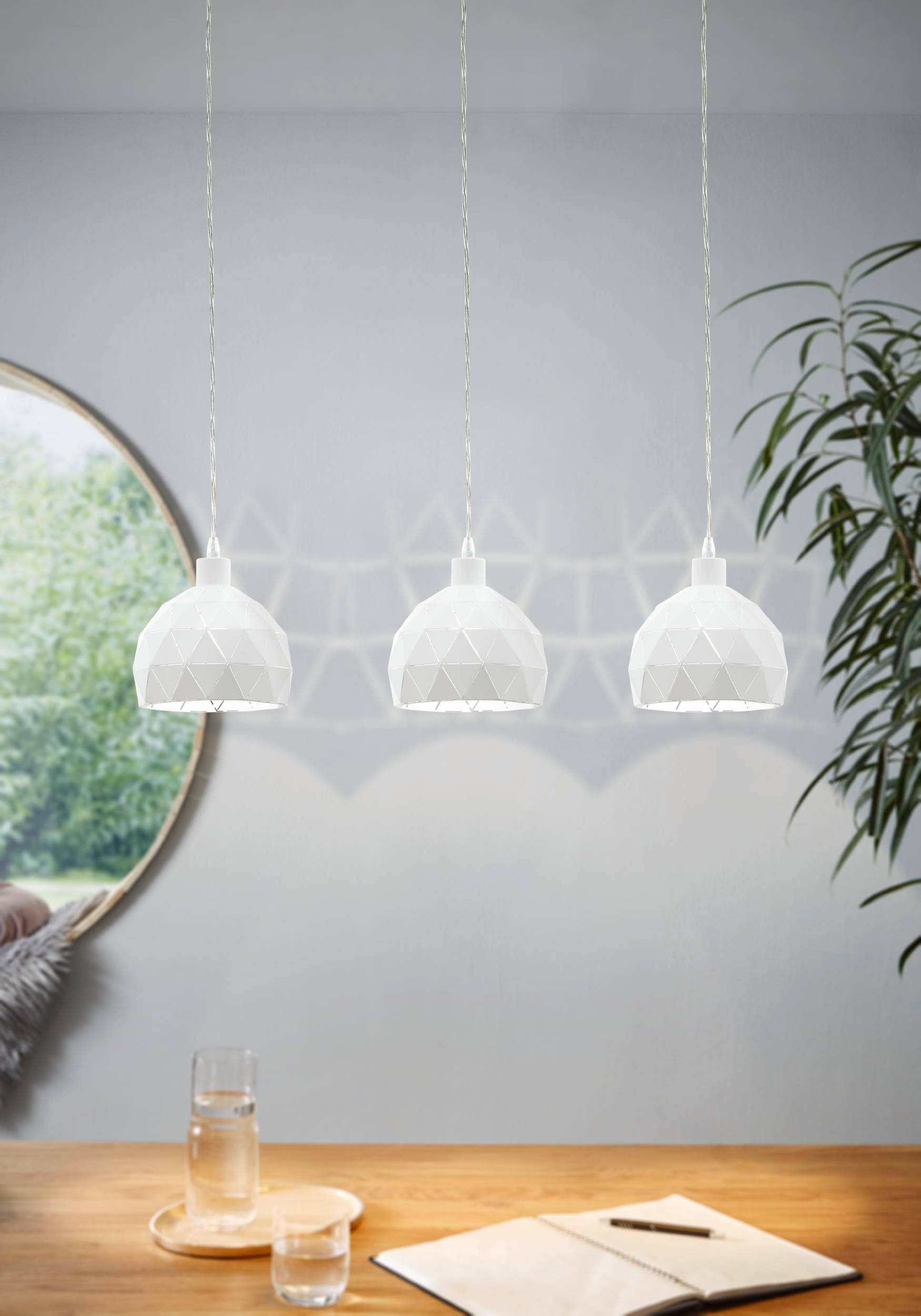 Drei weiße geometrische Pendelleuchten hängen über einem Holztisch in einem modernen Essbereich.
