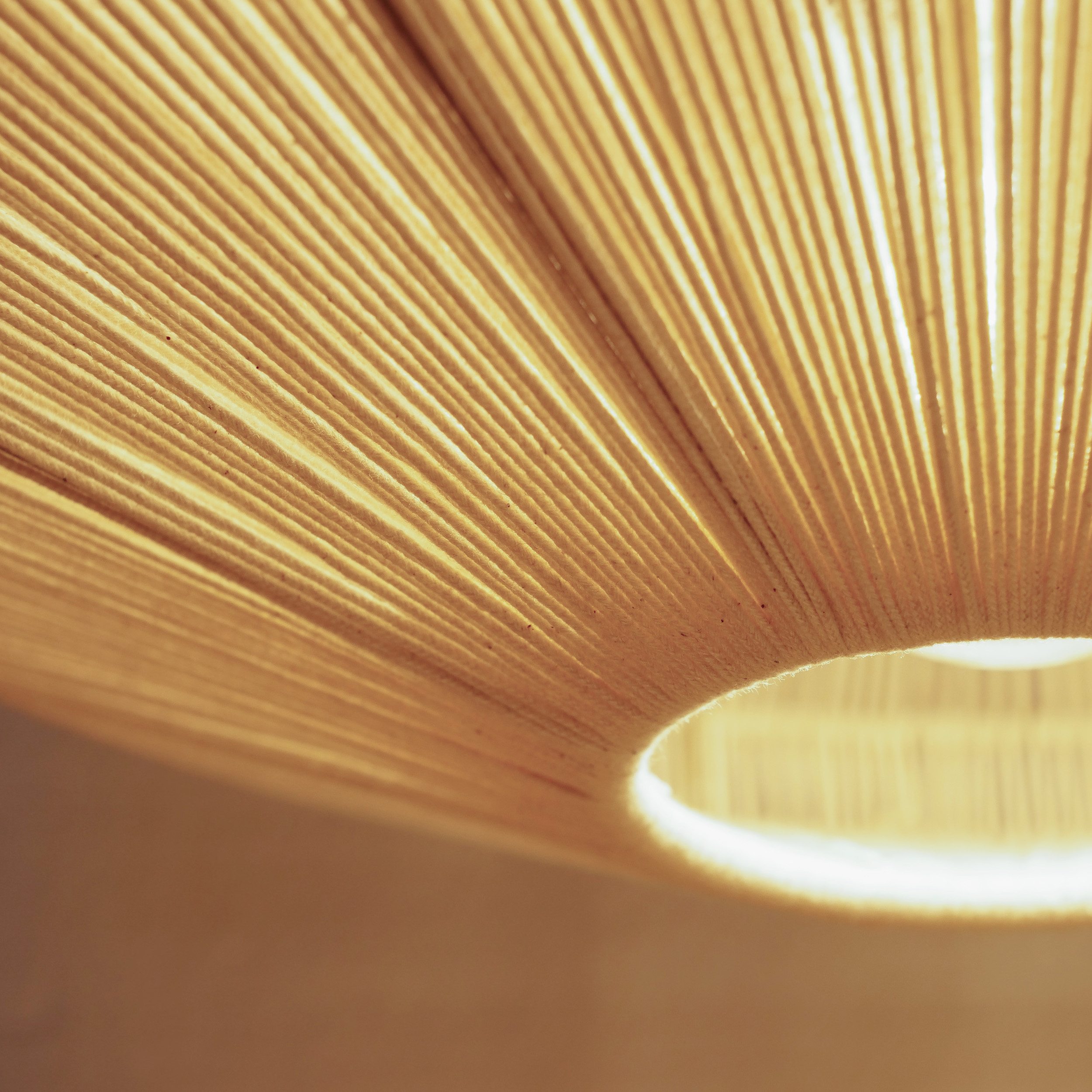 Un primo piano di una lampada a sospensione in corda beige, che mostra la sua texture e il suo design.