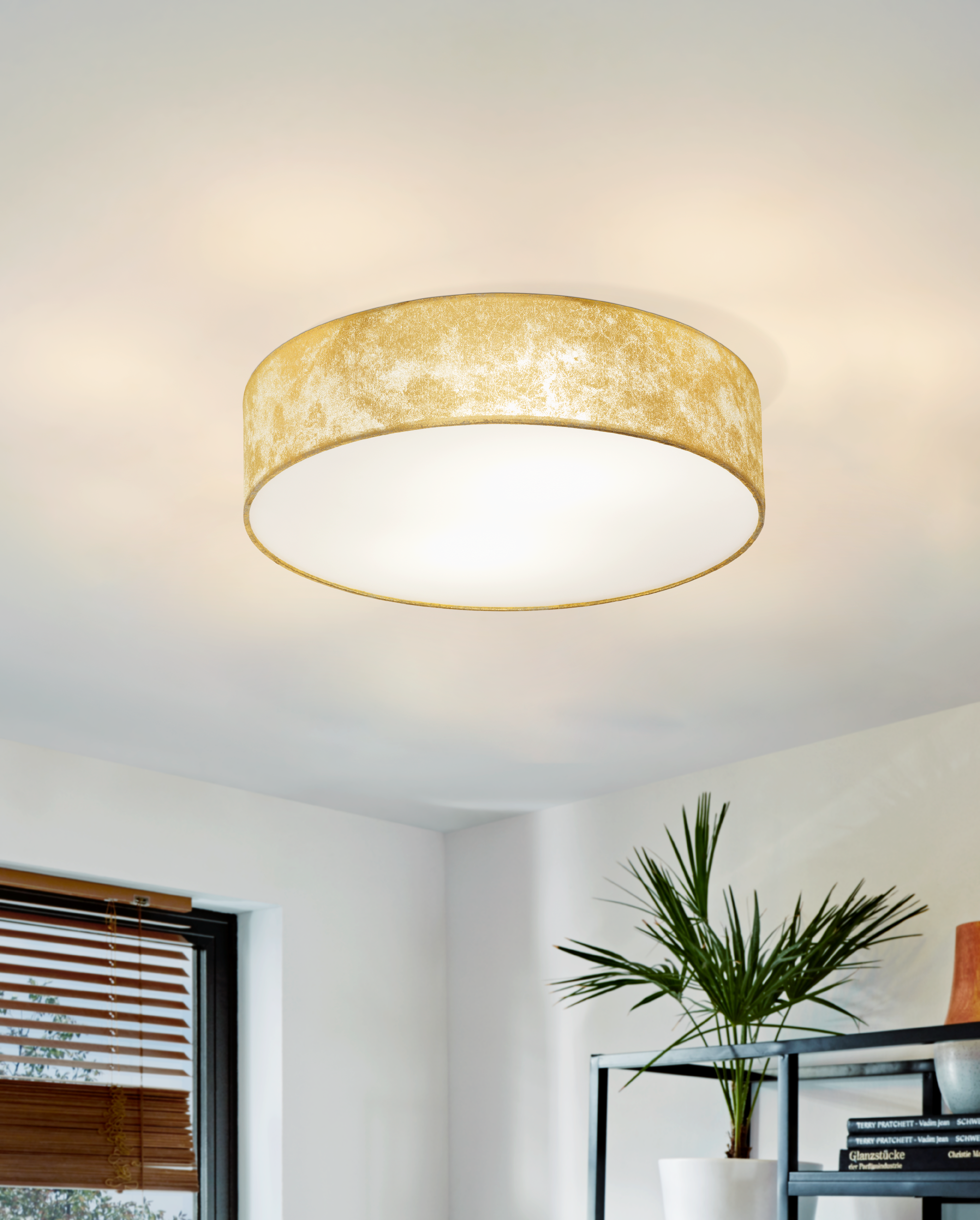 Eine goldene Deckenleuchte mit weißem Innenraum ist an einer weißen Decke montiert.