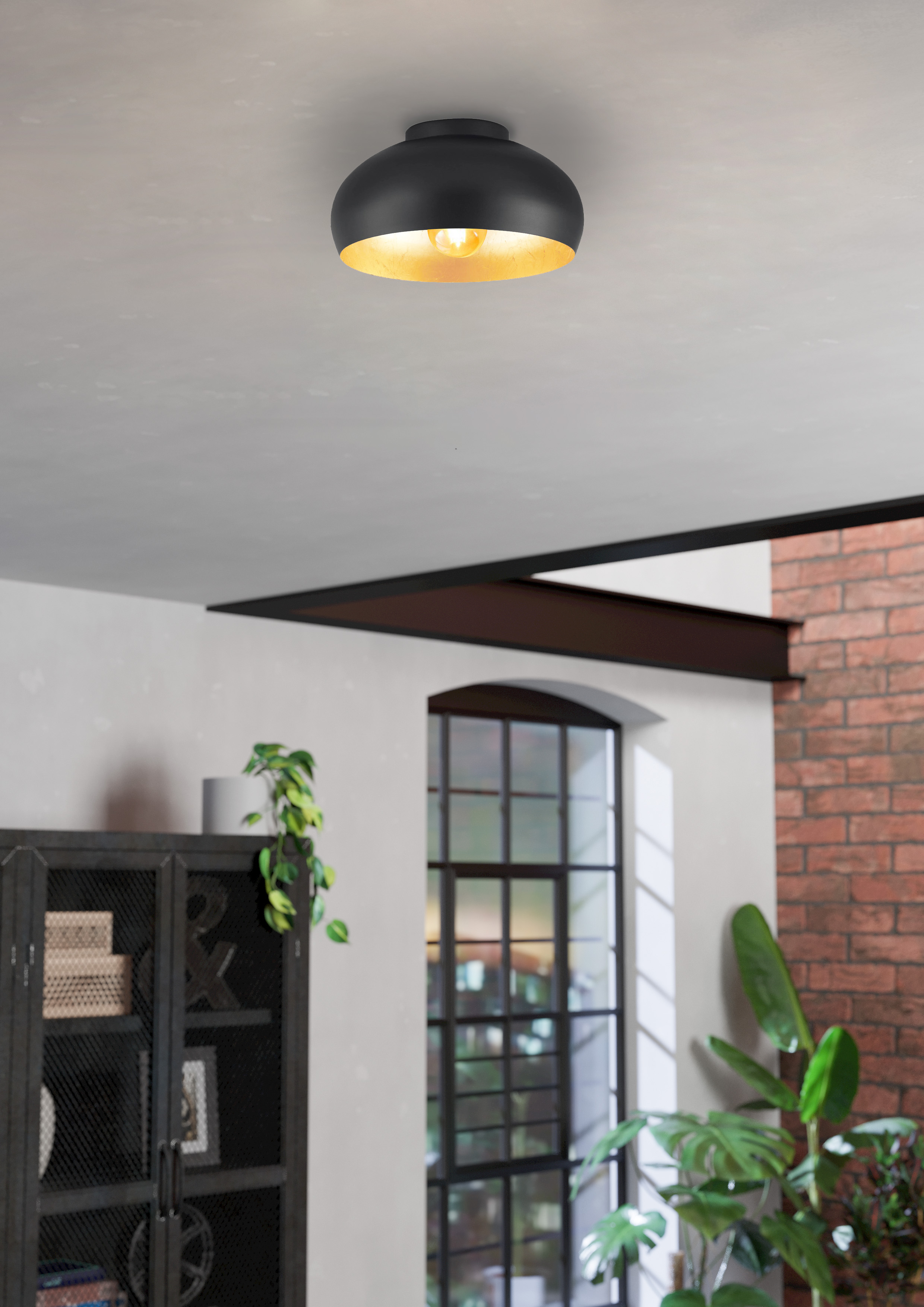 Lampada da soffitto nera con interno dorato. Visibile in una stanza con pareti bianche.