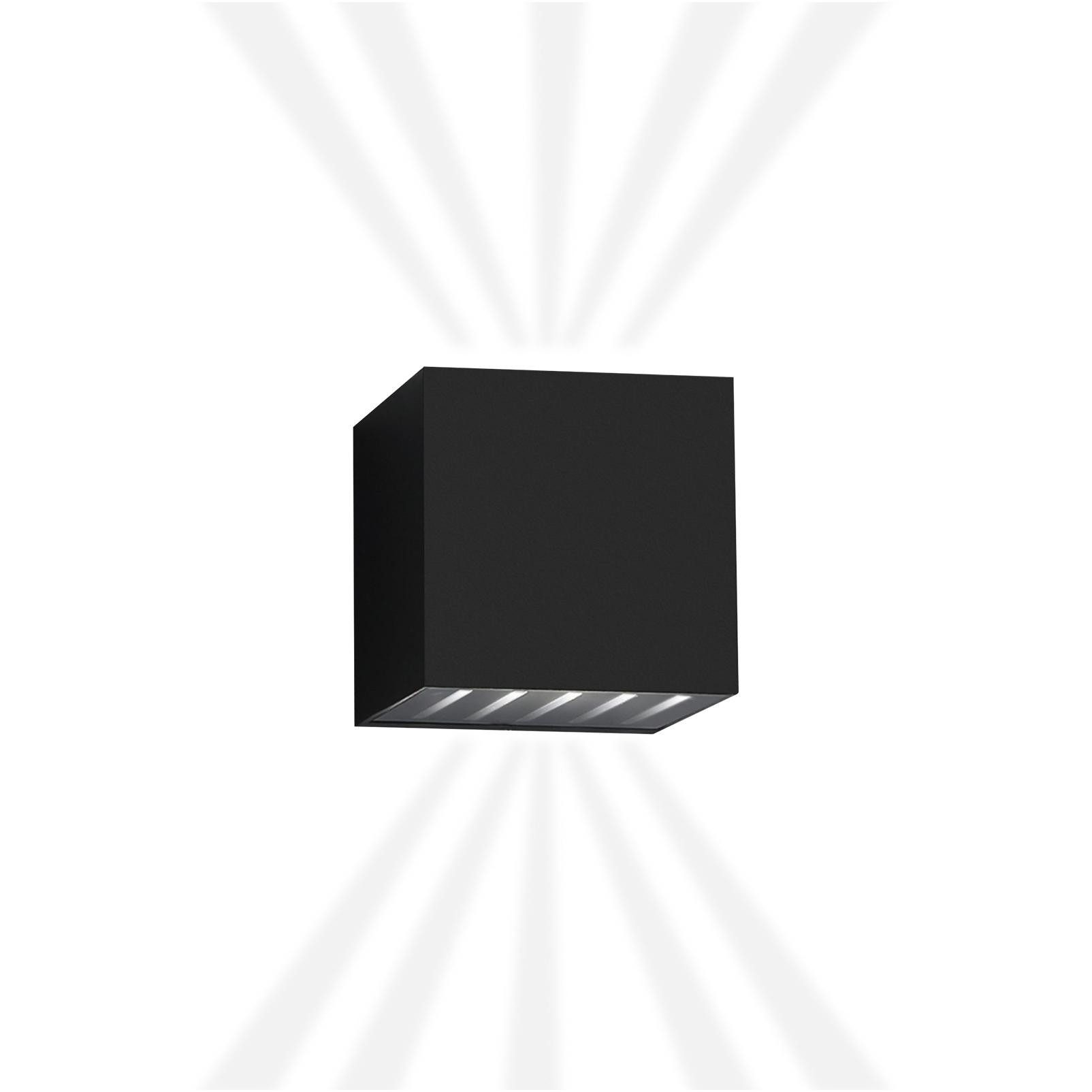 Una lampada da parete nera a forma di cubo emette fasci di luce verso l'alto e verso il basso contro uno sfondo bianco.