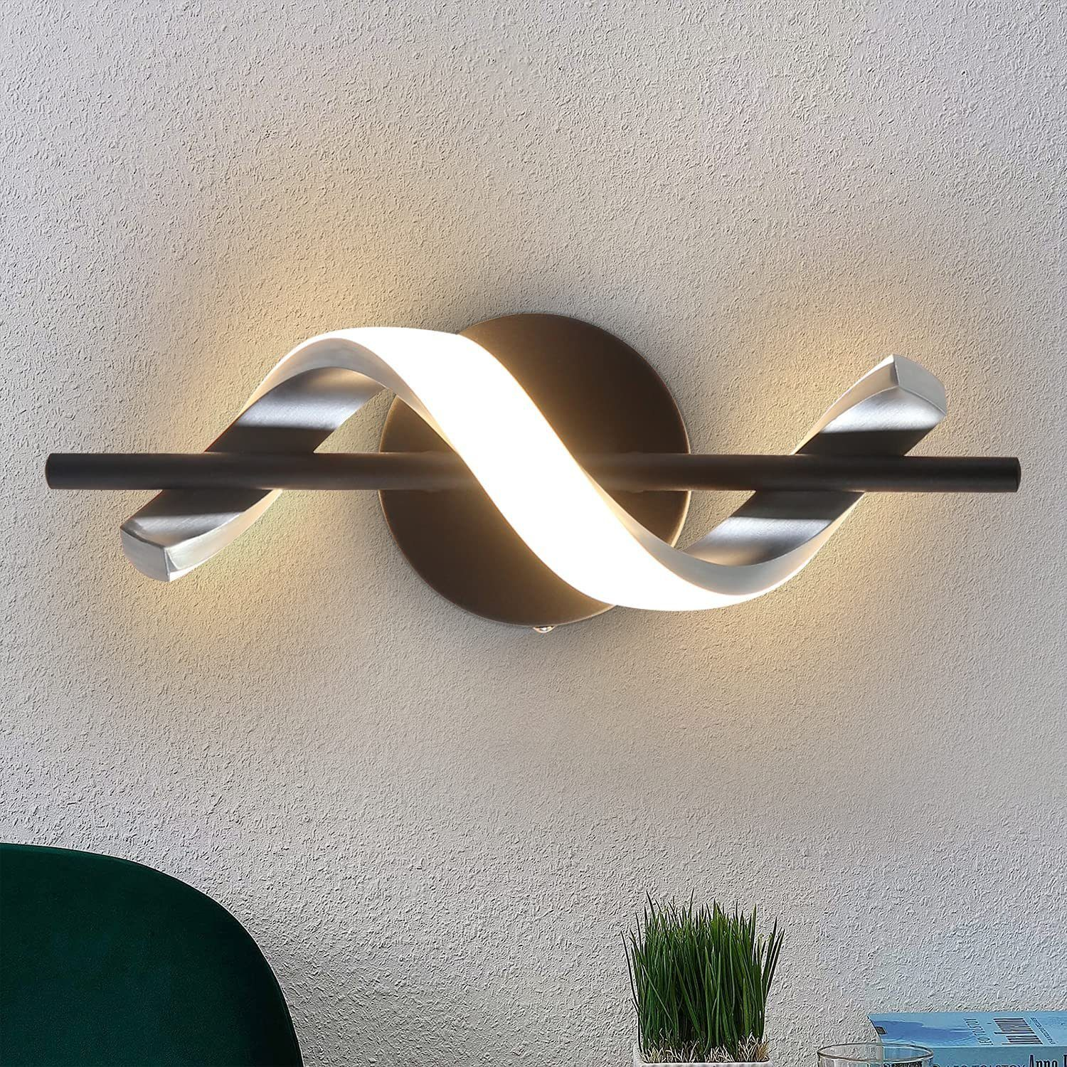 Una moderna lampada da parete con un design curvo, elementi neri e argentati e una luce intensa.