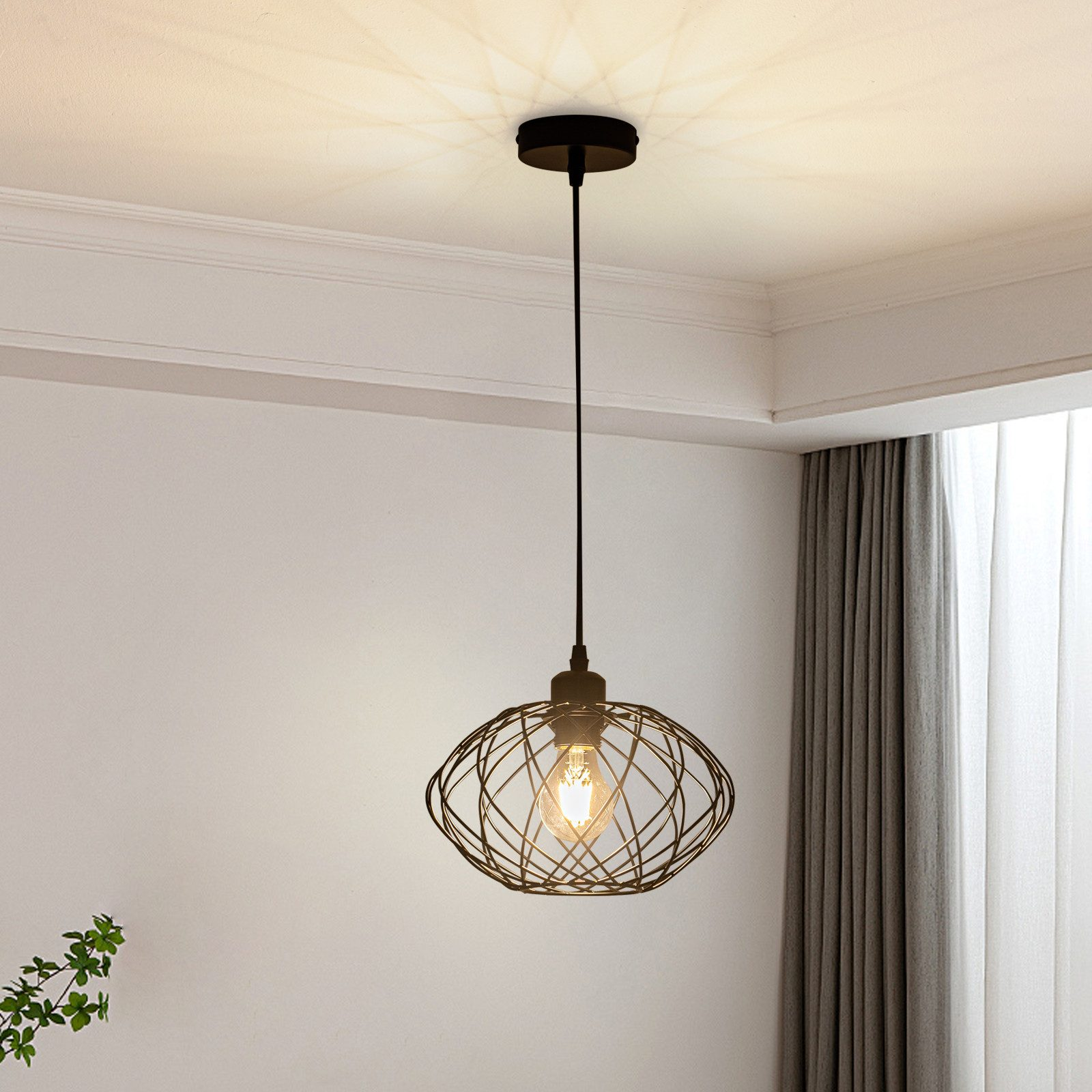 Eine schwarze Pendelleuchte mit Drahtgestell. Sie hängt von der Decke in einem Raum.
