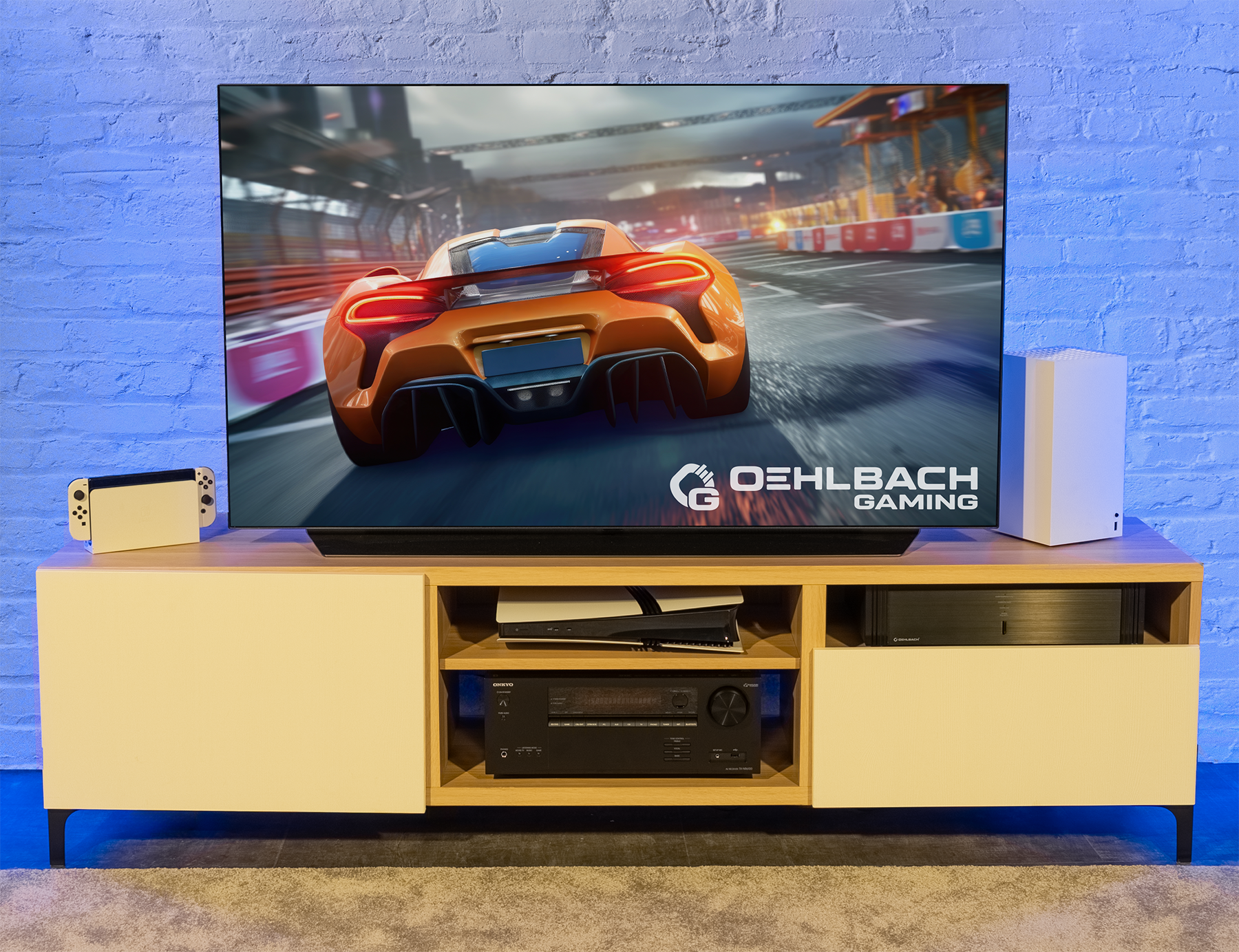 Wohnzimmer-Setup mit Fernseher, Konsole und Spielgeräten auf einem Holzständer vor einer Ziegelmauer.