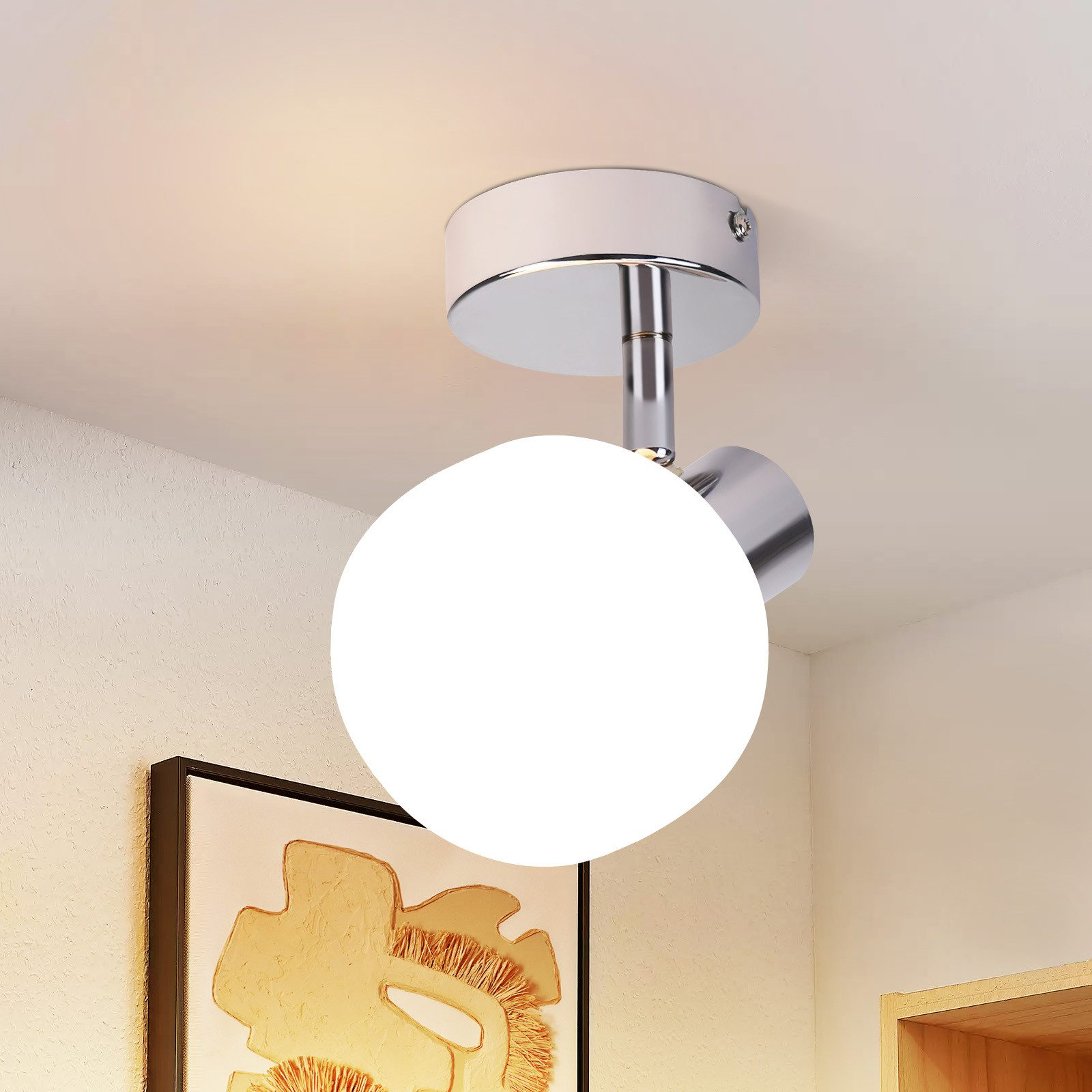 Una lampada da soffitto a globo bianco è montata su un soffitto bianco con un'immagine incorniciata sulla parete sottostante.