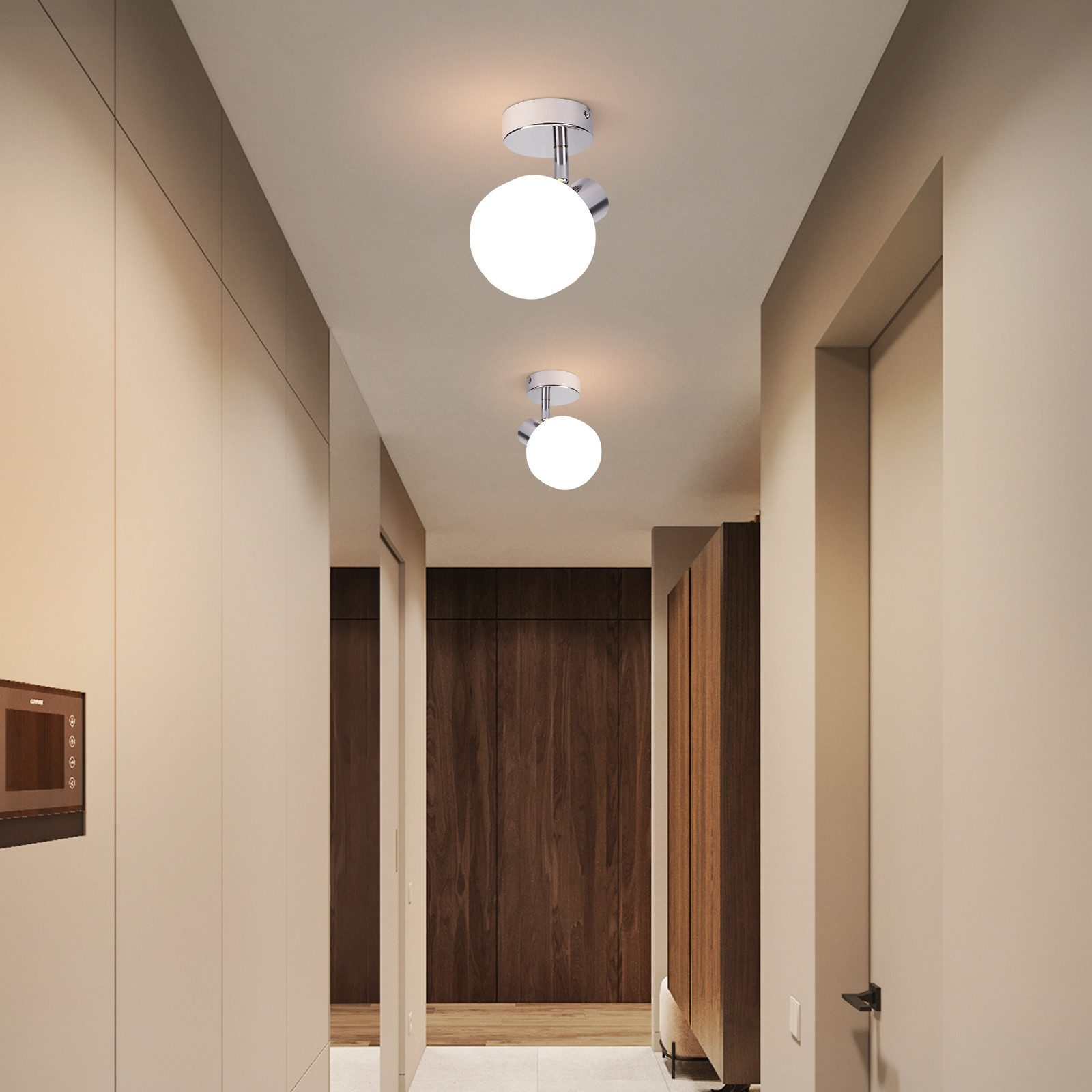 Due lampade da soffitto a globo bianco illuminano un corridoio con pareti beige e porte e finiture in legno scuro.