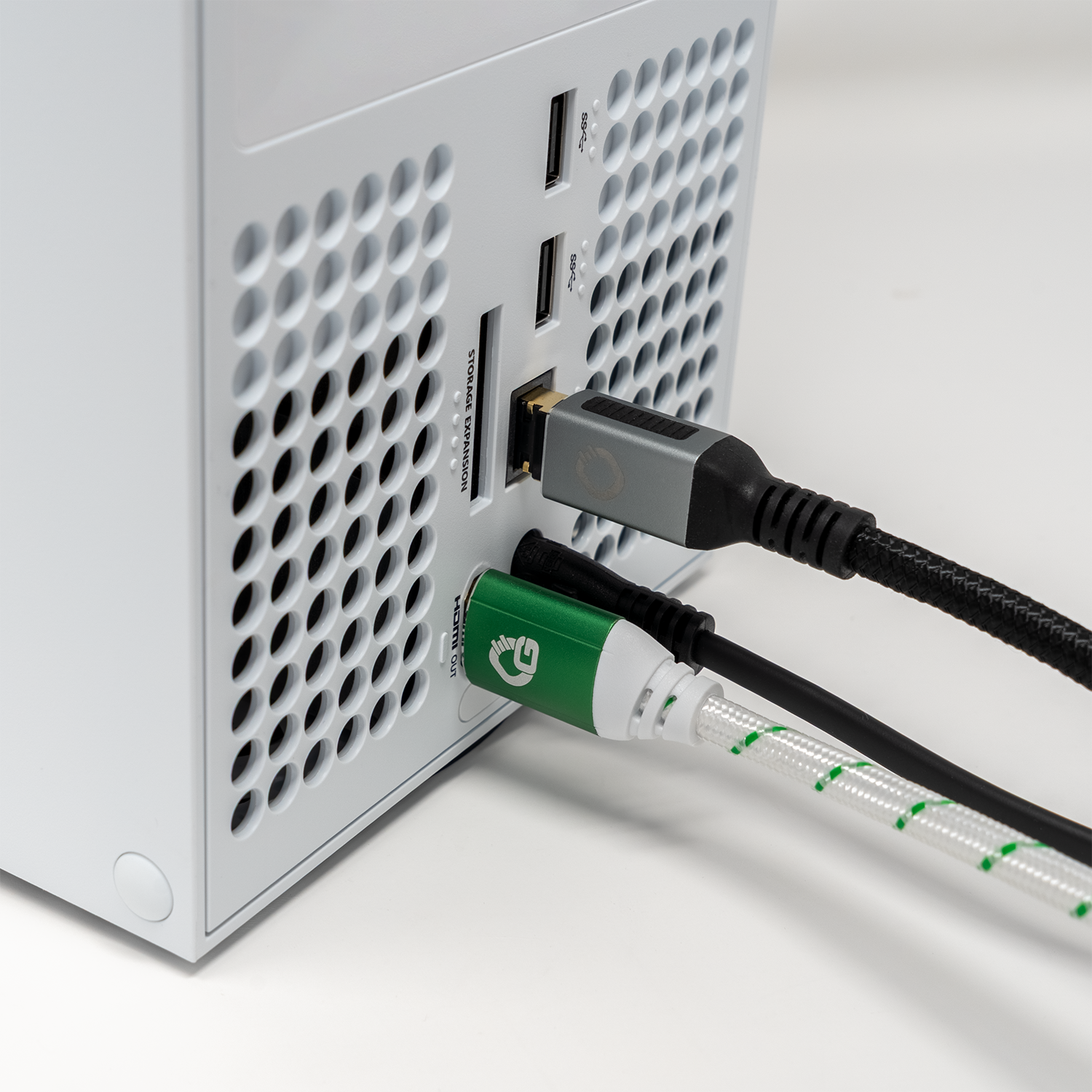 Die Rückseite einer weißen Spielekonsole mit angeschlossenen Kabeln. Ein grün-weißes HDMI-Kabel ist eingesteckt.