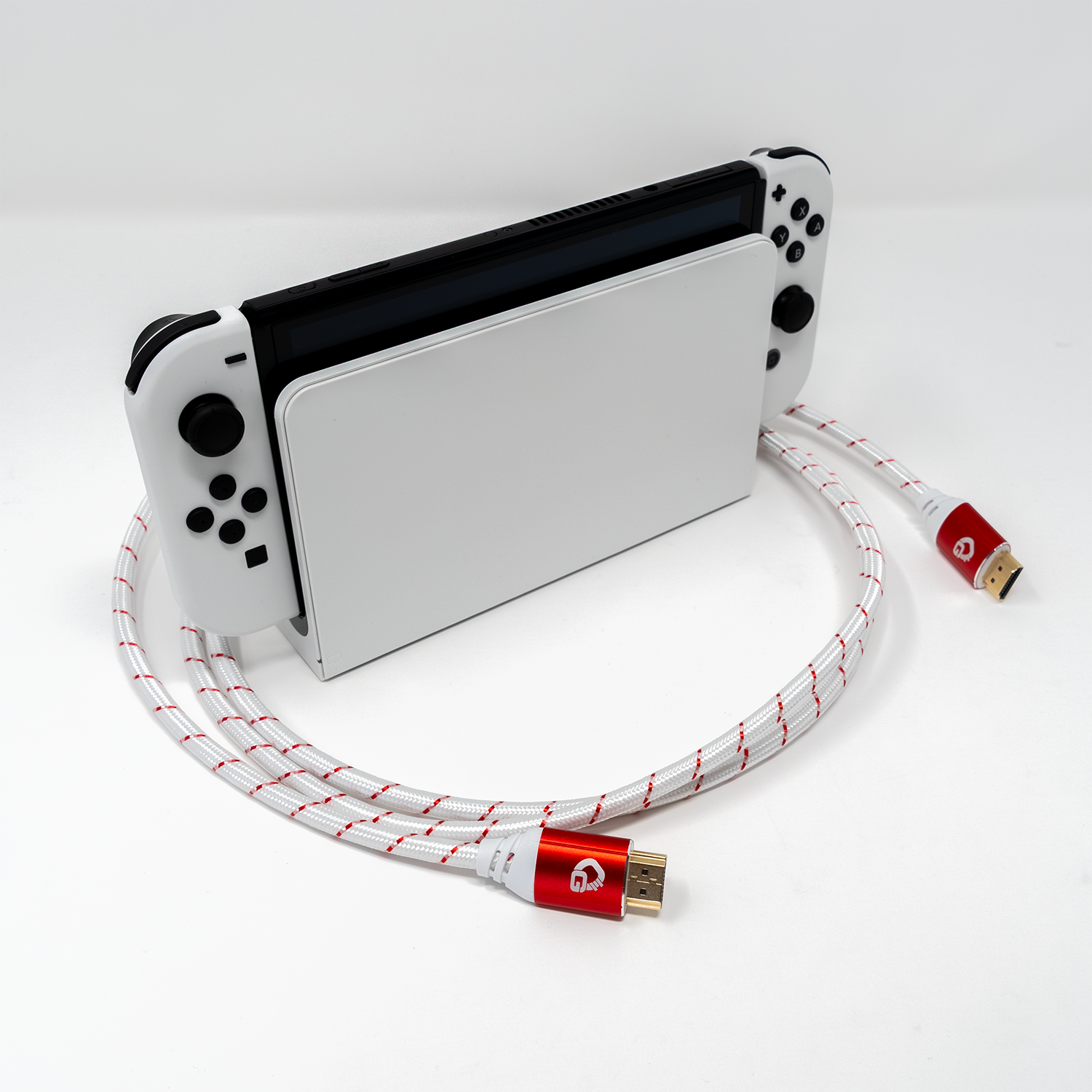 Weißer Nintendo Switch im Dock mit rot-weißem HDMI-Kabel auf einer weißen Oberfläche.