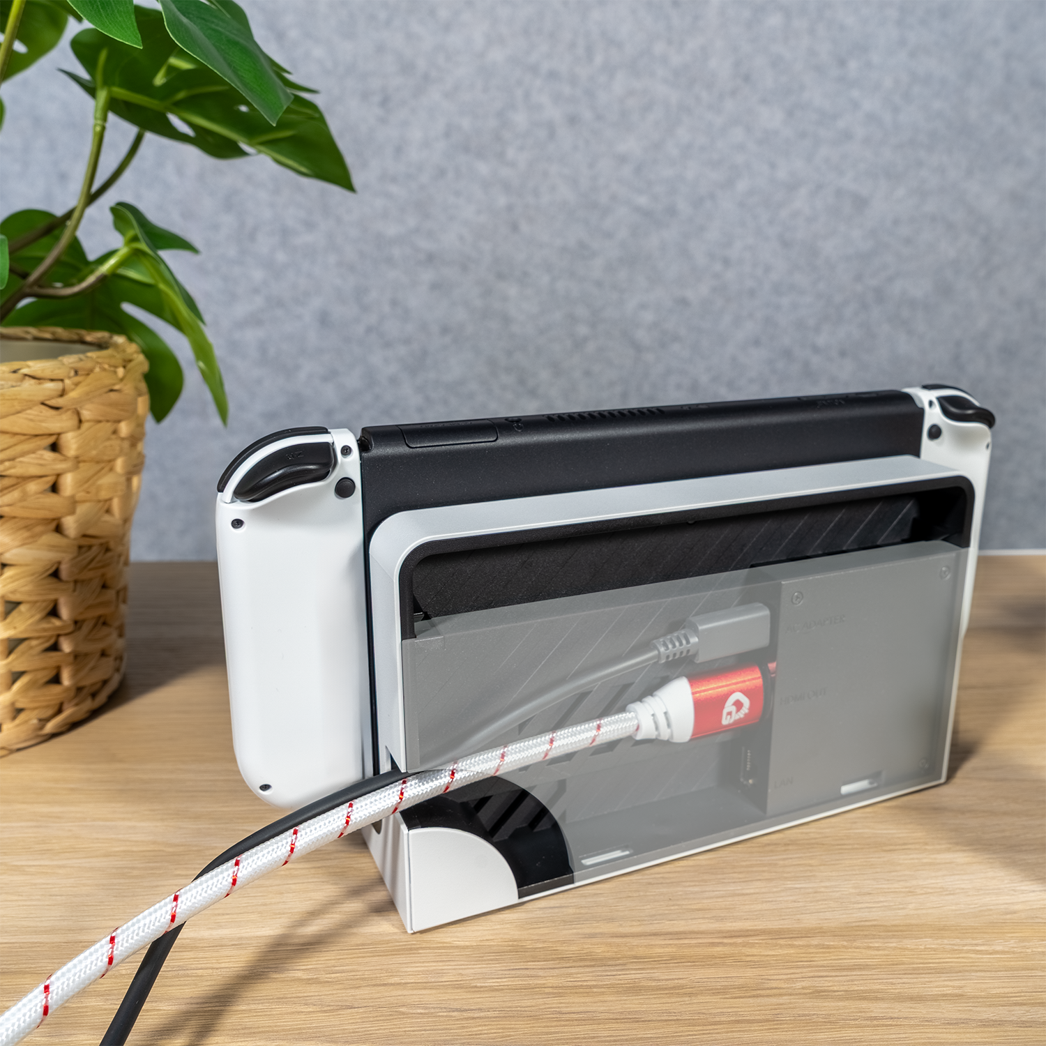 Rückseite des weißen Nintendo Switch im Dock mit rotem HDMI-Kabel auf Holzoberfläche.