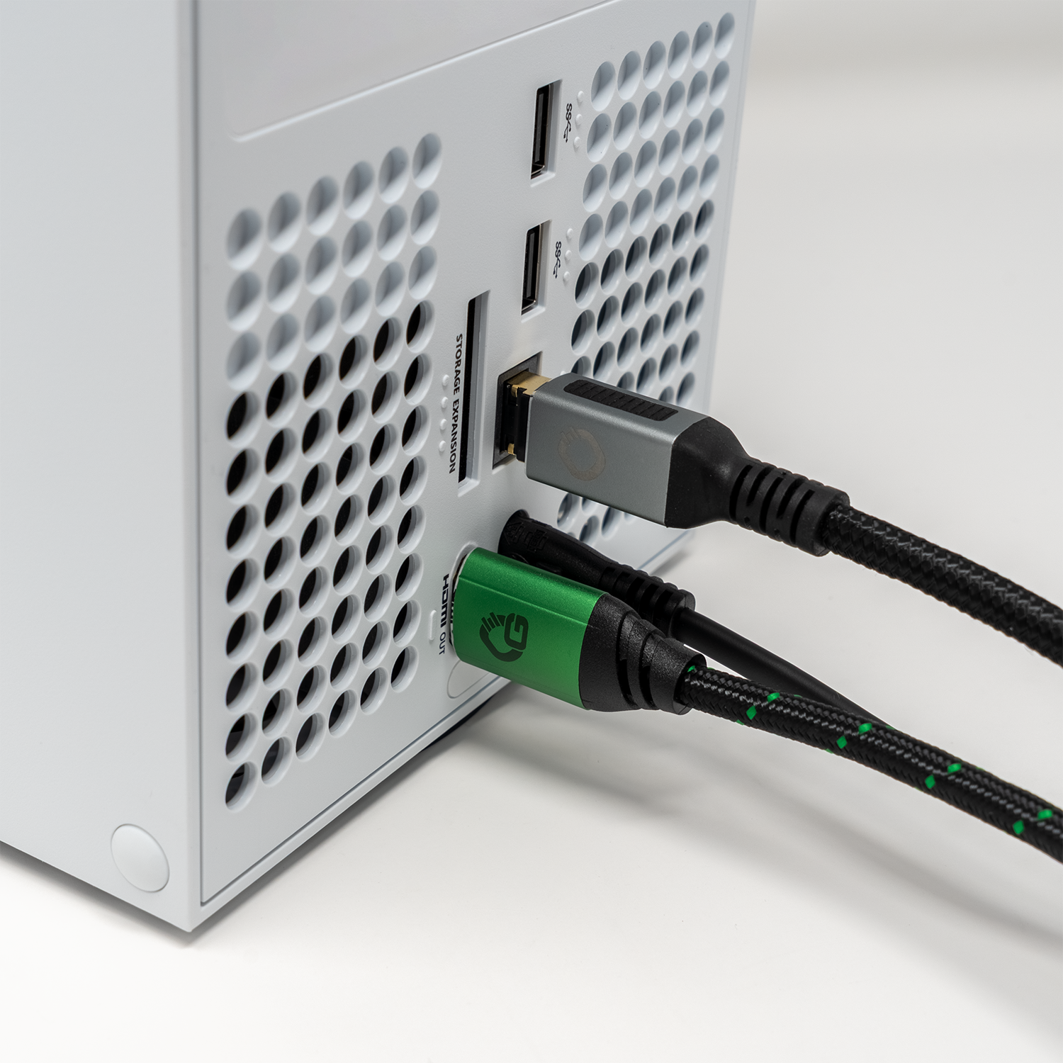 Weiße Spielekonsole mit mehreren Anschlüssen, mit angeschlossenen HDMI-Kabeln.