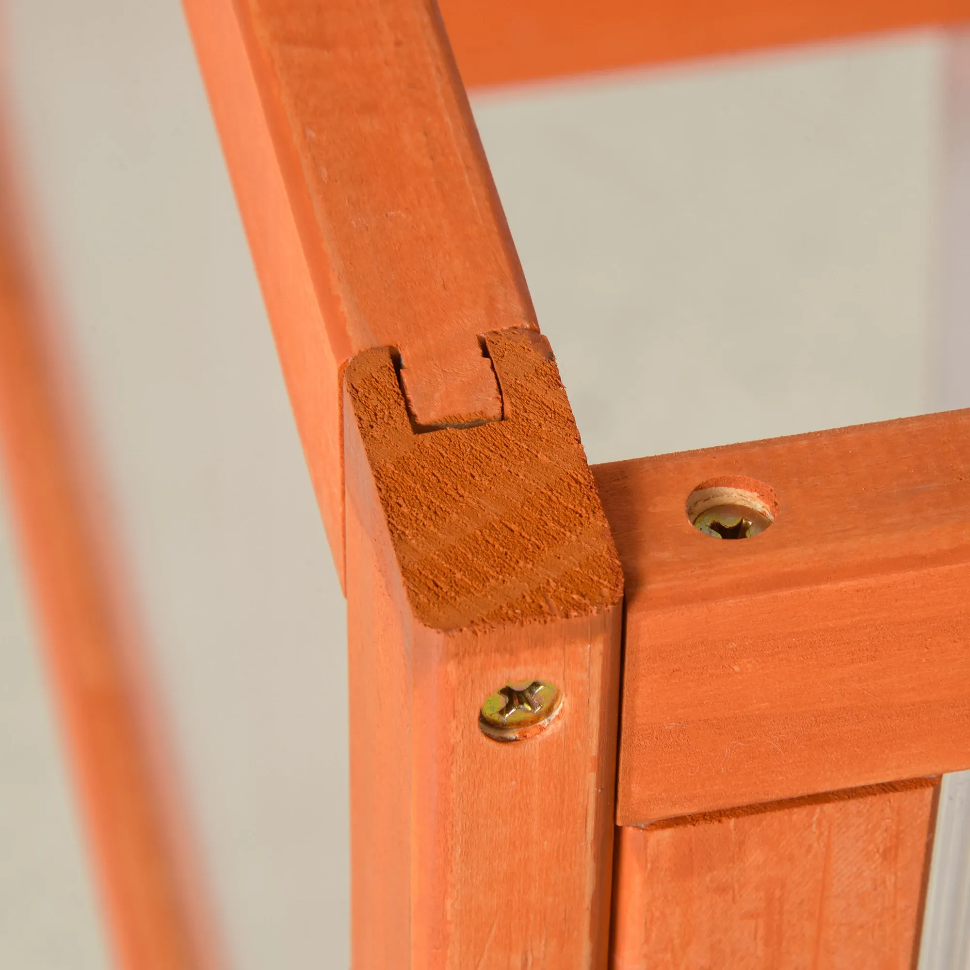 Nahaufnahme einer orangefarbenen Holzeckverbindung mit Schrauben, die detaillierte Konstruktion und Textur zeigt.