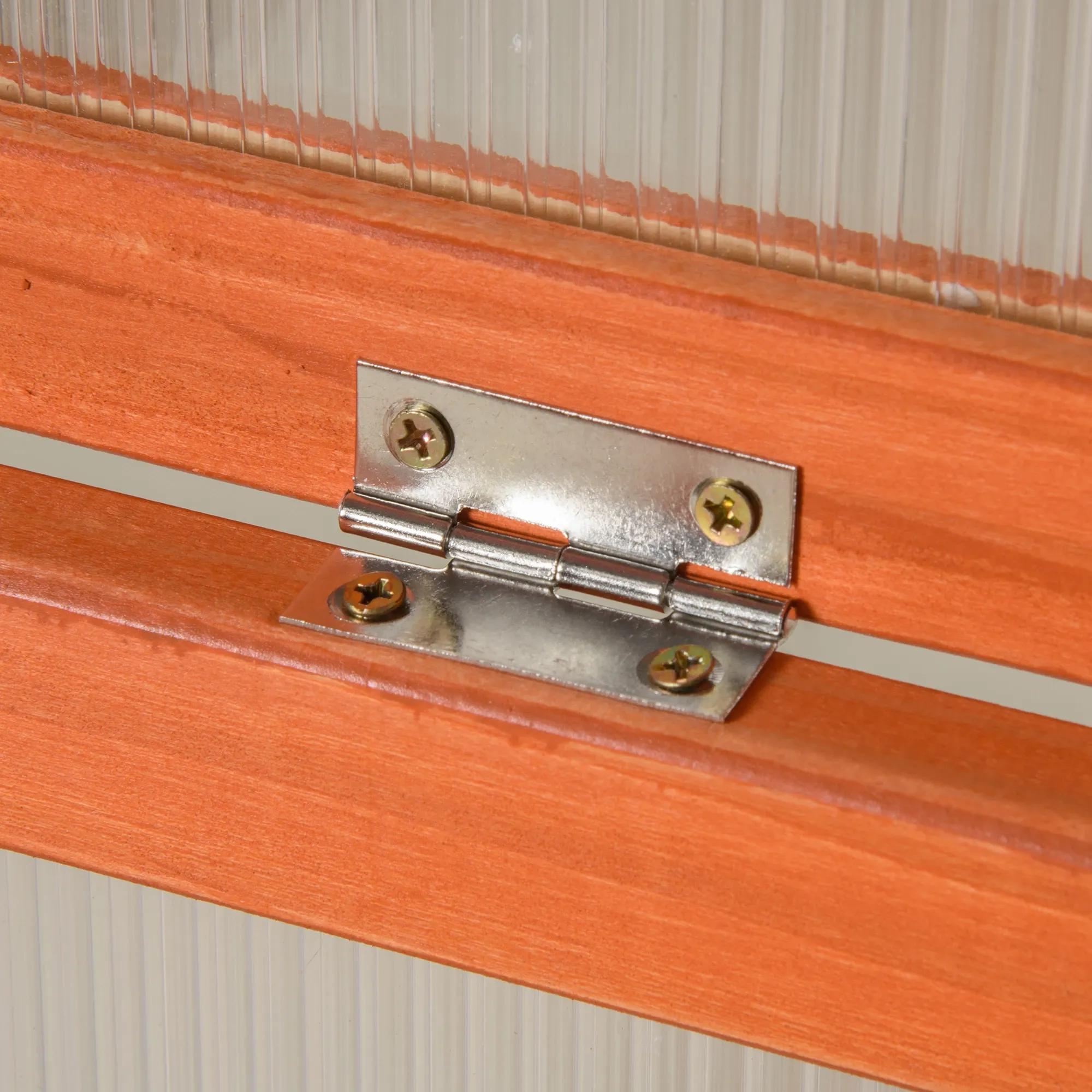 Nahaufnahme eines silbernen Scharniers, das mit Schrauben an einem Holzrahmen befestigt ist und Hardware-Details zeigt.