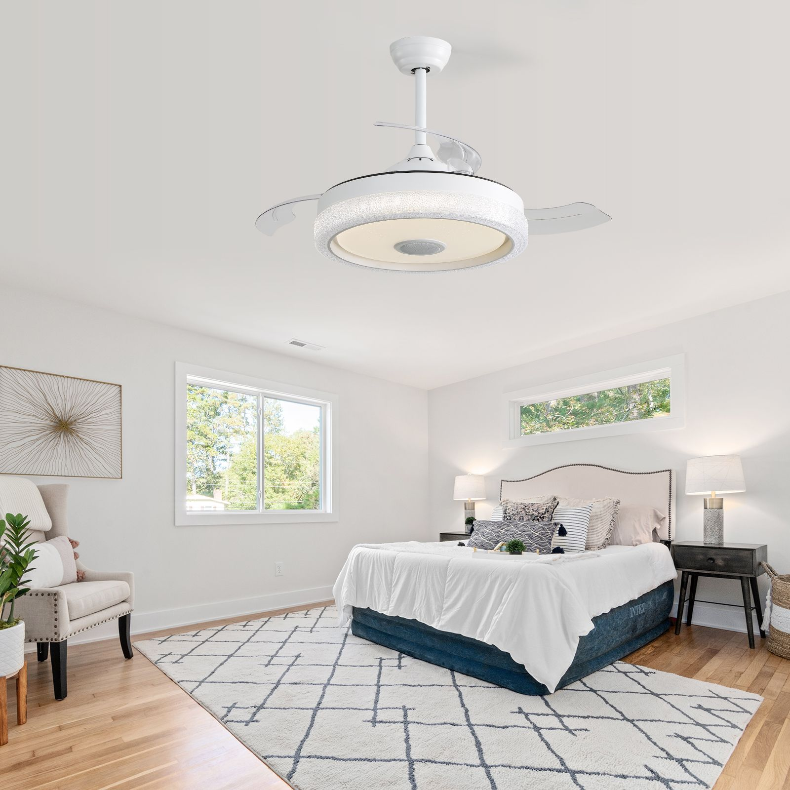 Ein Schlafzimmer mit Deckenventilator, Bett und Fenstern. Der Raum ist hell und luftig.