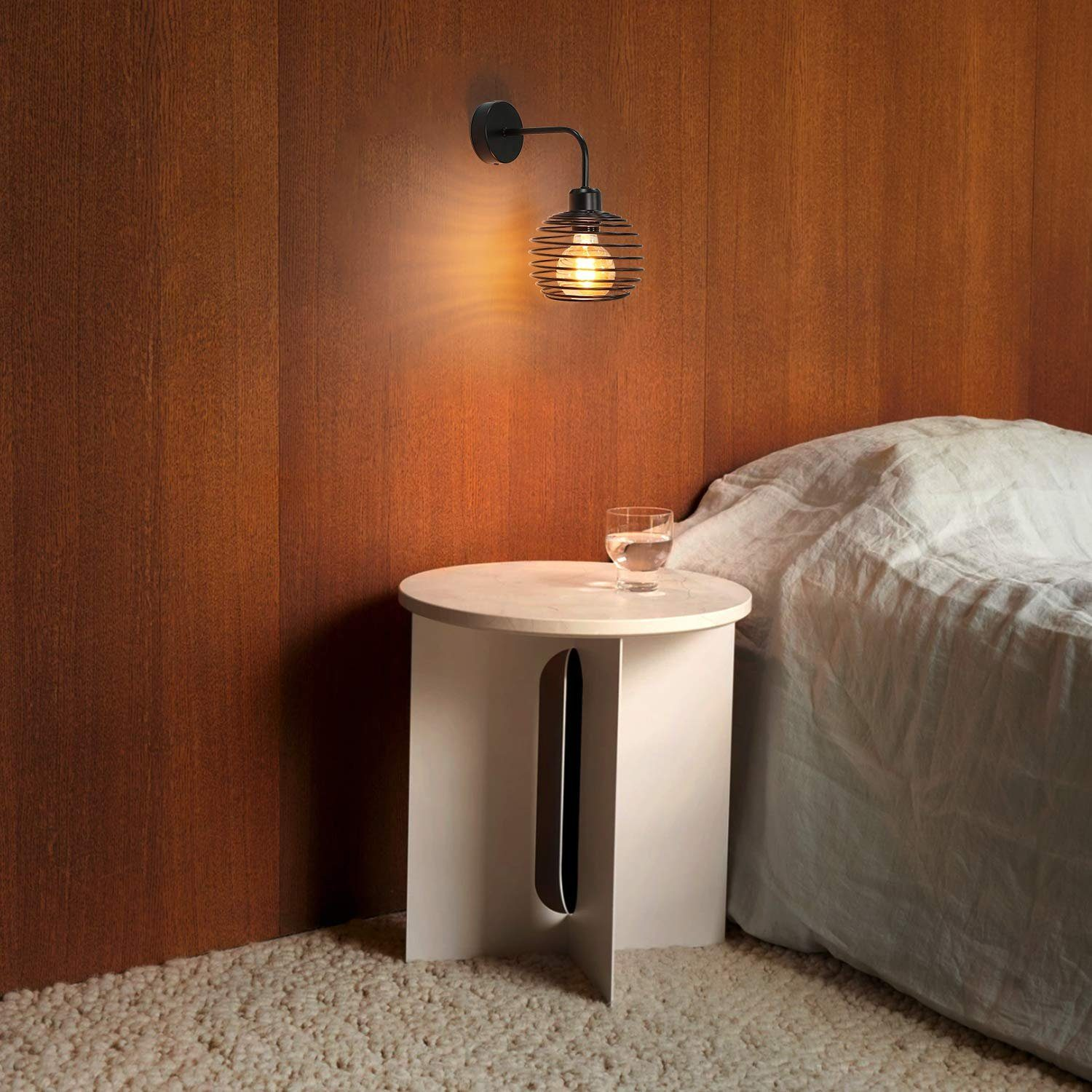 Lampada da parete a gabbia, lampadina accesa, su parete in legno, vicino a letto e tavolo.