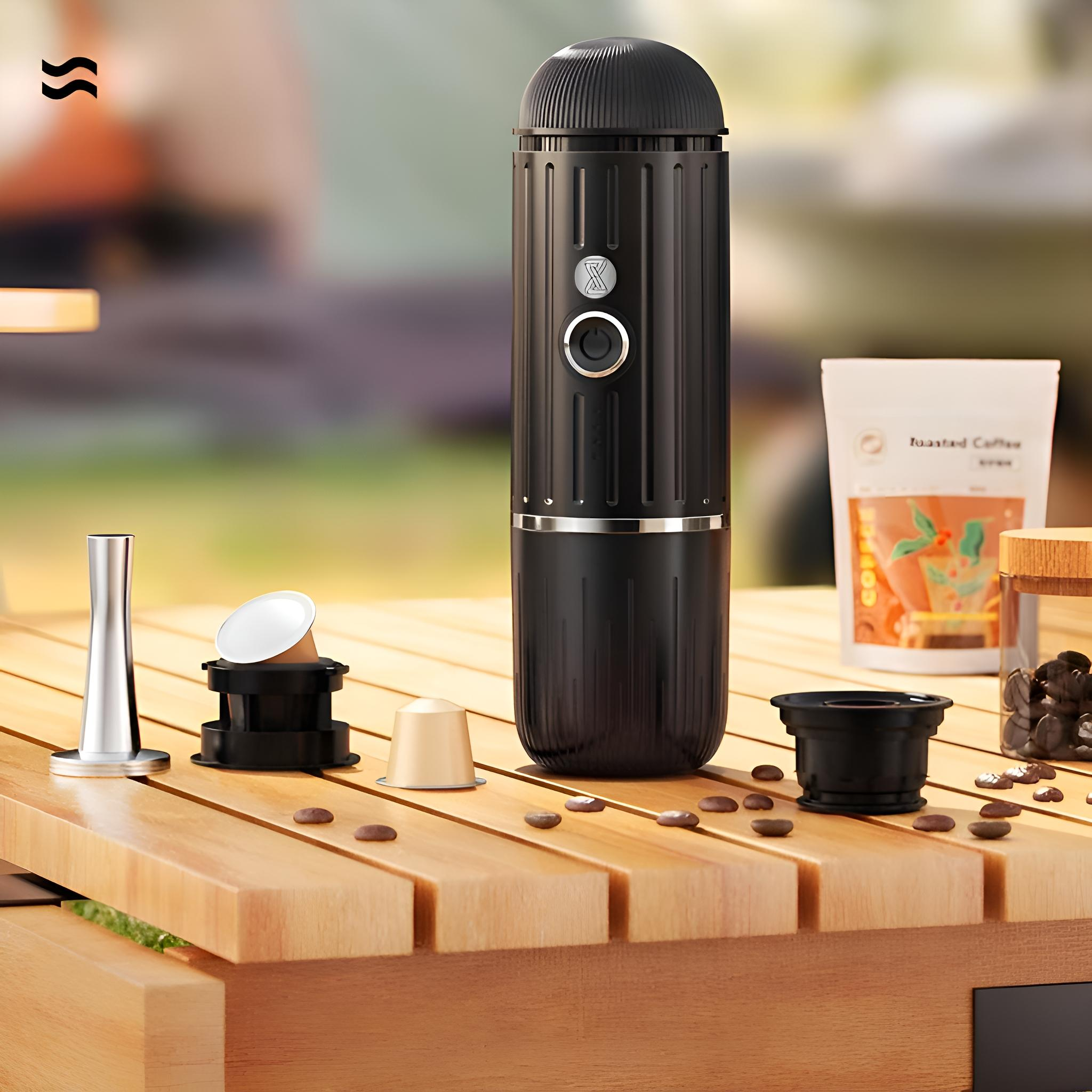 Tragbarer schwarzer Espressokocher auf einem Holztisch mit Kaffeebohnen und Verpackung.