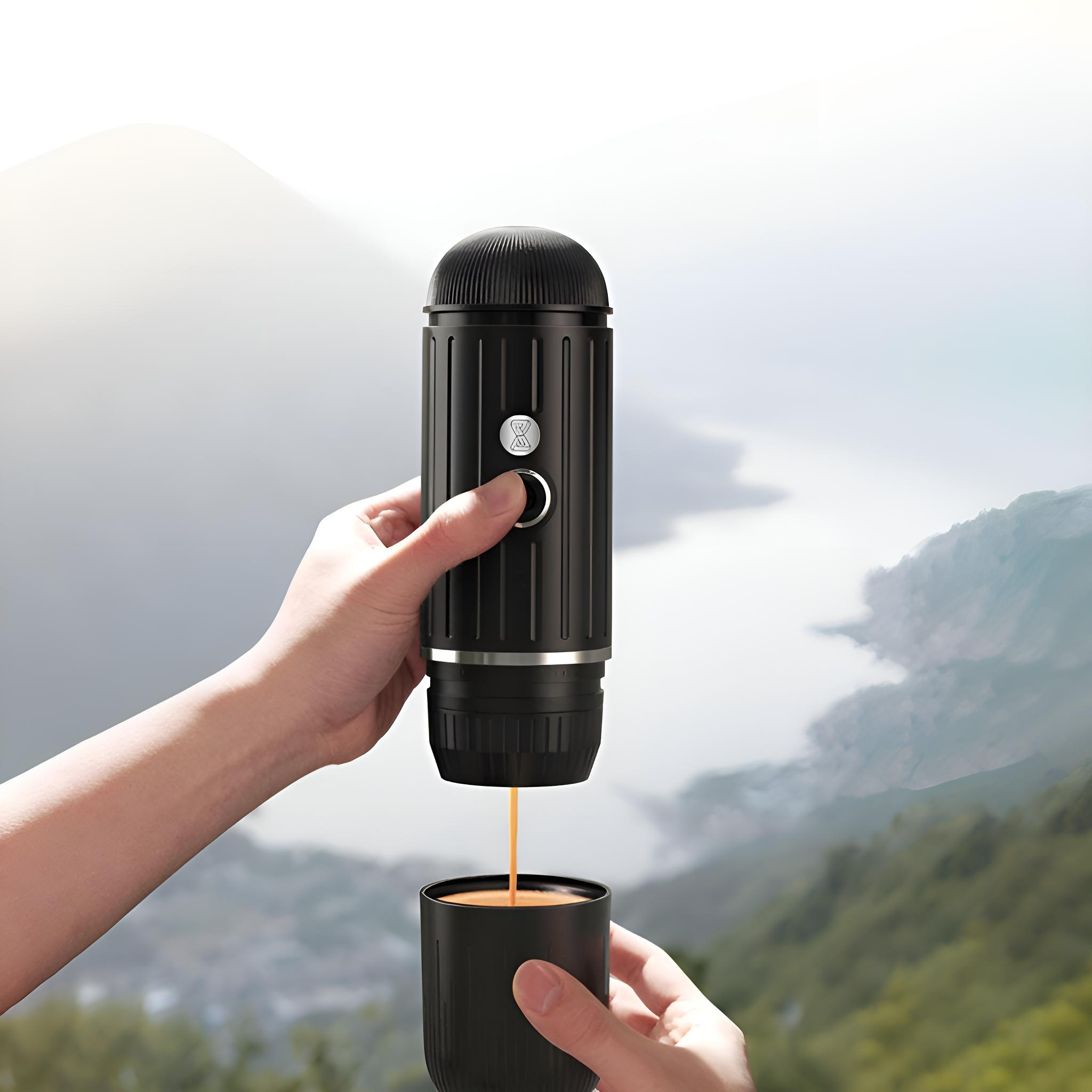 Tragbare Espressomaschine, die Kaffee in eine schwarze Tasse gießt, vor einer Bergkulisse.