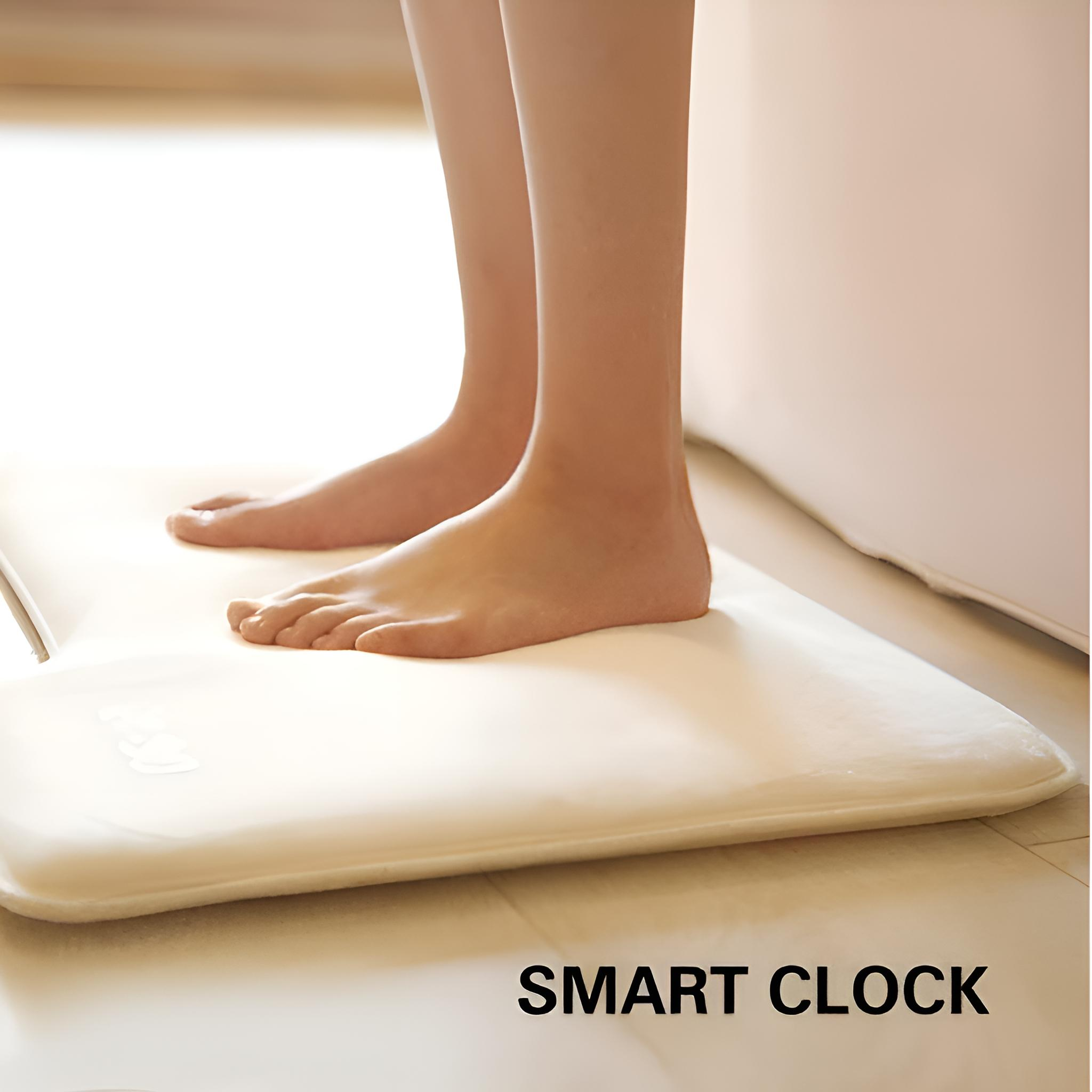 Nackte Füße stehen auf einer weißen Smart-Clock-Matte vor einer weißen Badewanne.