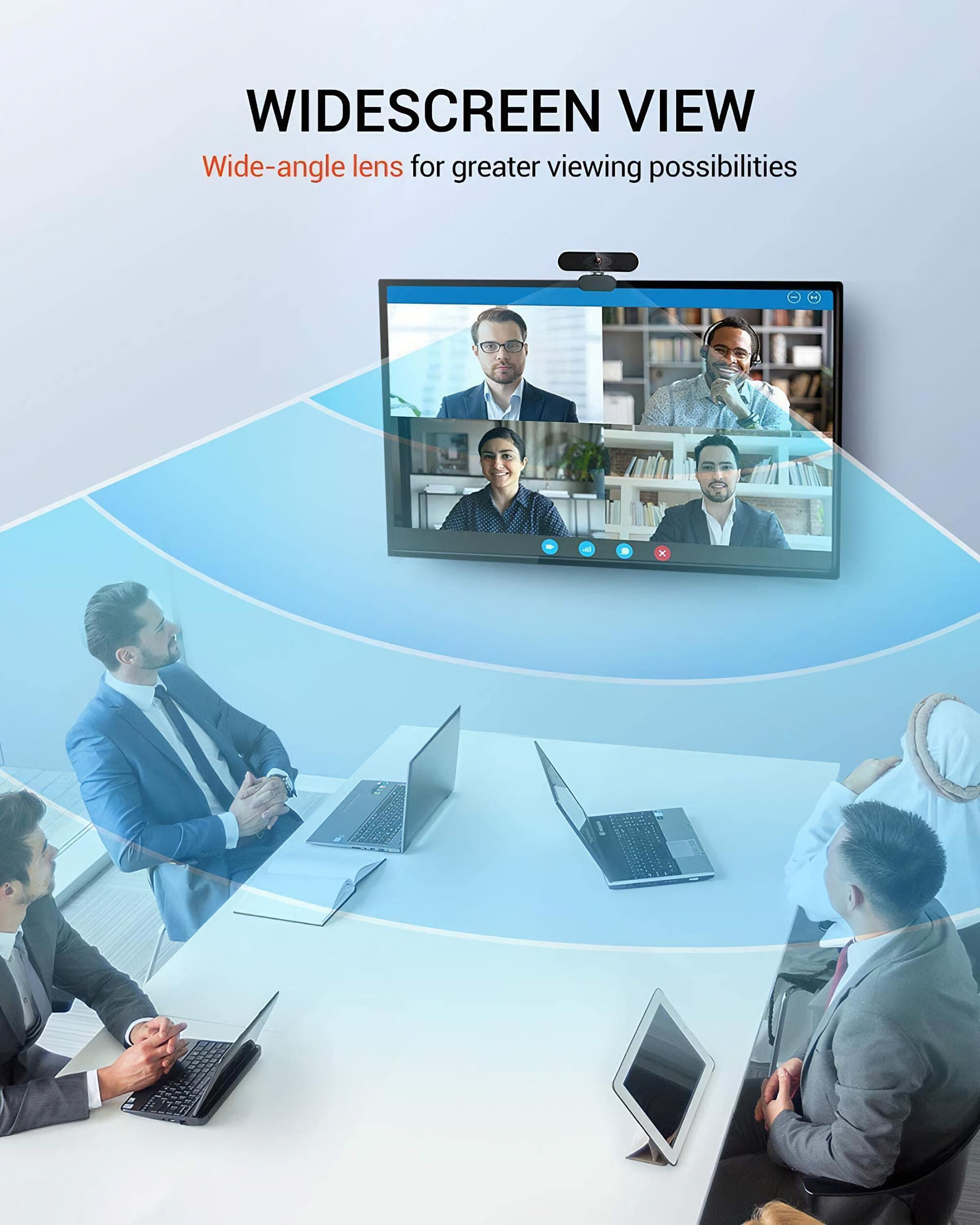 Eine Weitwinkelansicht eines Meetings. Eine Webcam oben auf einem Monitor und Personen in einem Konferenzraum.