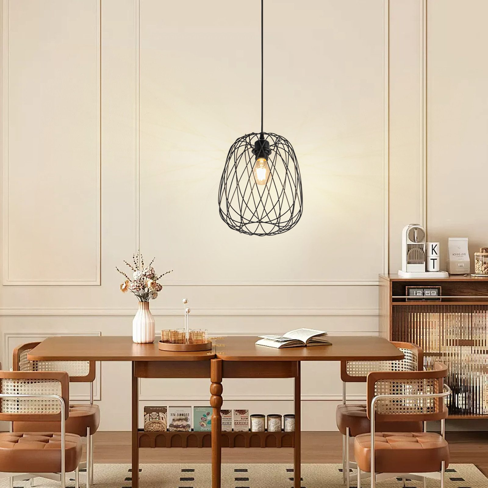 Una lampada a sospensione in filo nero illumina un tavolo da pranzo in una stanza dai toni neutri.