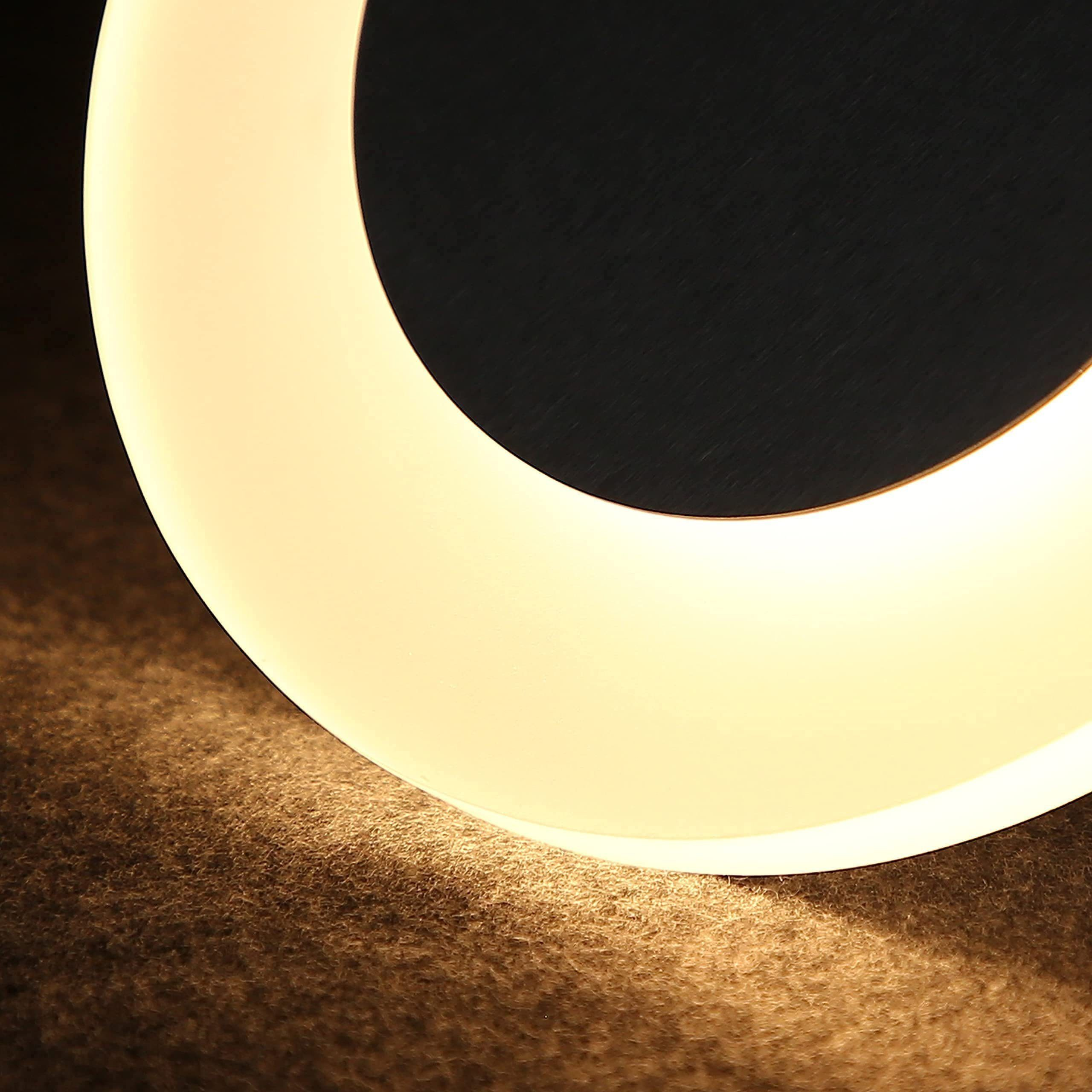 Primo piano di una lampada da parete circolare con una calda luce su una superficie ruvida.