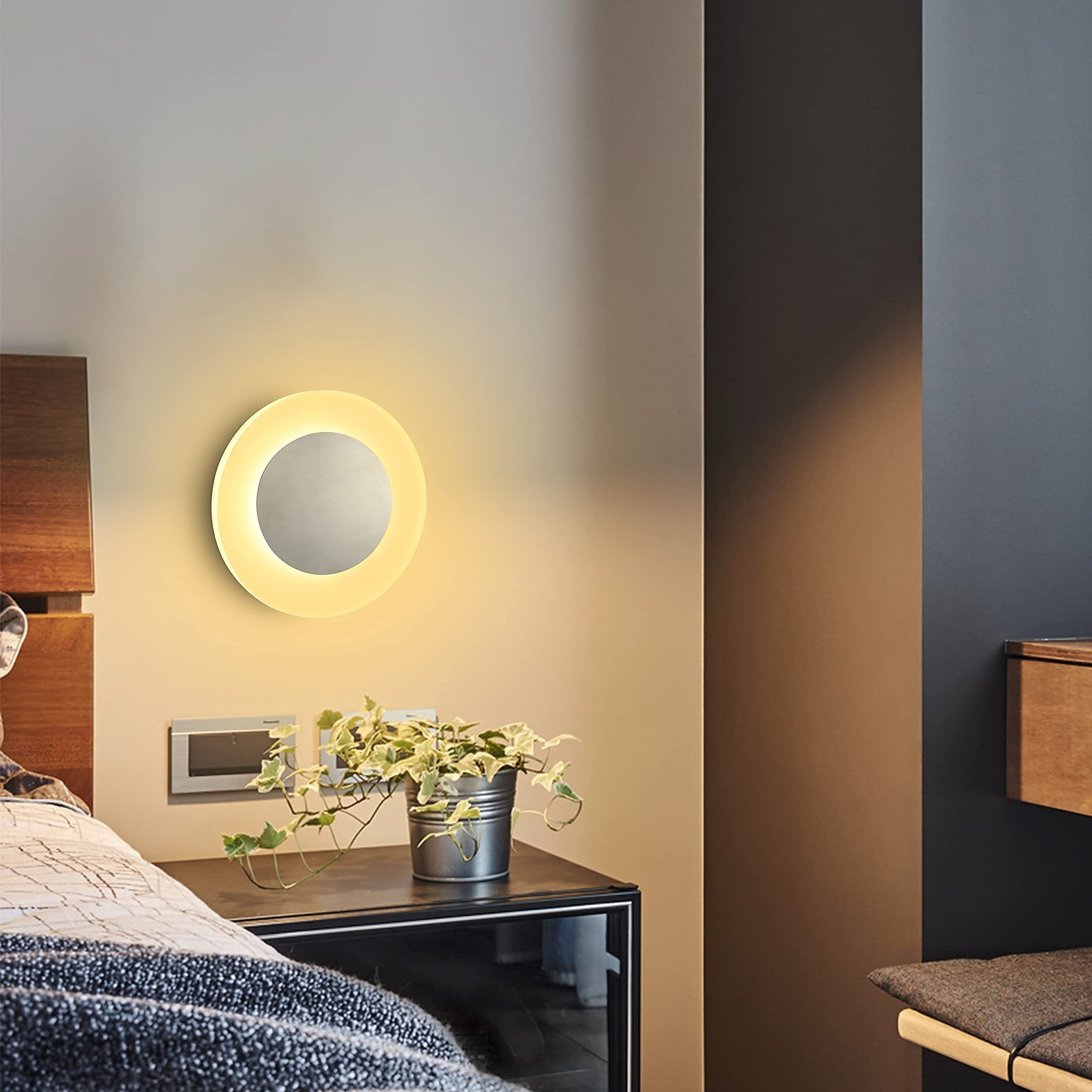 Scena di camera da letto con una lampada da parete circolare sopra un comodino, che mostra un ambiente interno accogliente.