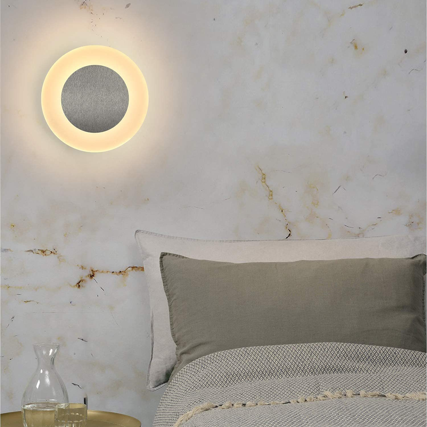 Interno della camera da letto con una lampada da parete circolare sopra il letto, creando un'atmosfera soffusa.