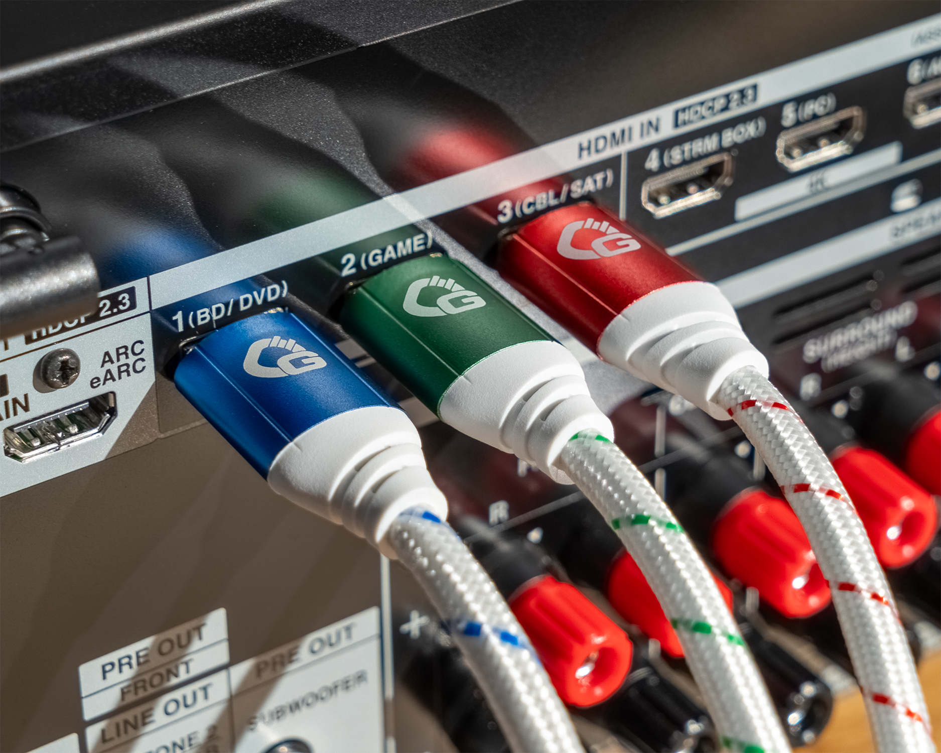 Nahaufnahme von drei HDMI-Kabeln mit farbigen Steckern, die in ein schwarzes Gerät eingesteckt sind, mit den Worten 'HDMI IN' sichtbar.
