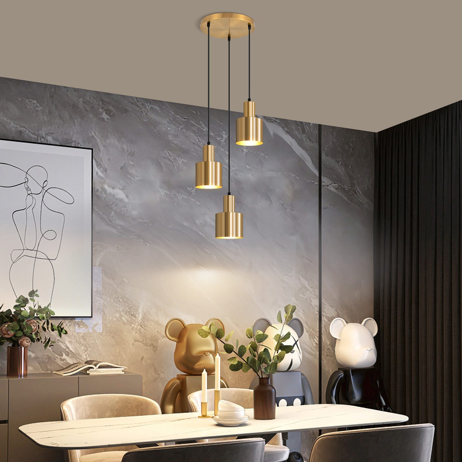 Una sala da pranzo presenta tre lampade a sospensione dorate sopra un tavolo con oggetti decorativi e sedie.
