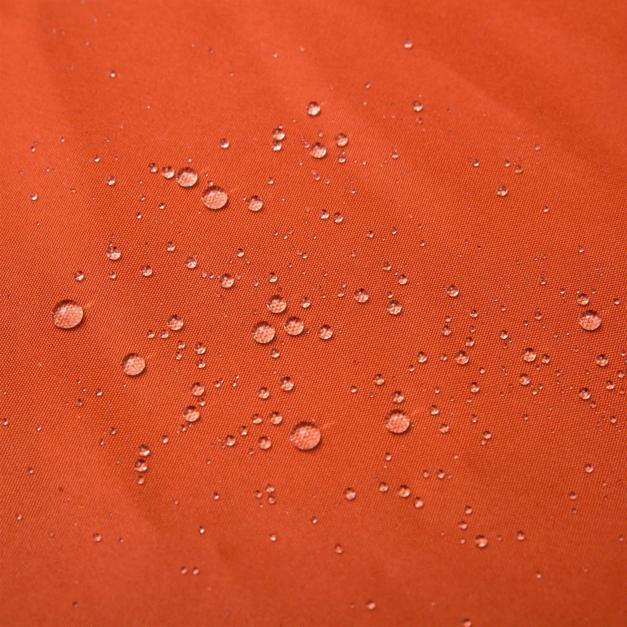Nahaufnahme von Wassertropfen auf einem rostfarbenen Pavillondach, die seine wasserabweisenden Eigenschaften zeigen.