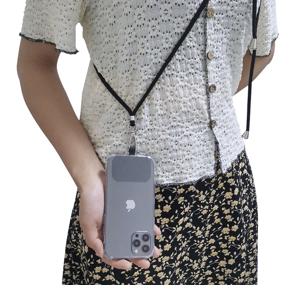 Eine Frau mit weißem Hemd und geblümtem Rock, die ein Handy an einem schwarzen Schlüsselband hält.