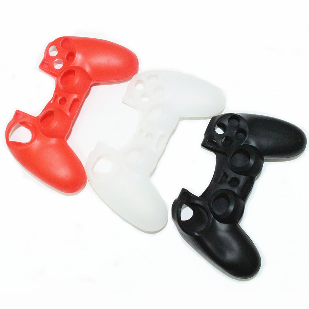 Drei Silikonhüllen für Gamecontroller in Rot, Weiß und Schwarz, auf einer weißen Oberfläche angeordnet.