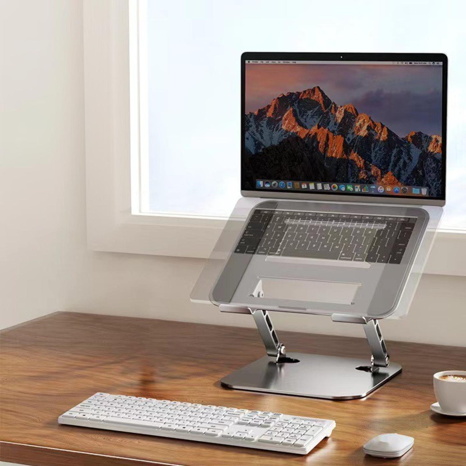 Laptop auf einem silbernen Ständer. Der Ständer steht auf einem Holzschreibtisch. Tastatur und Maus.