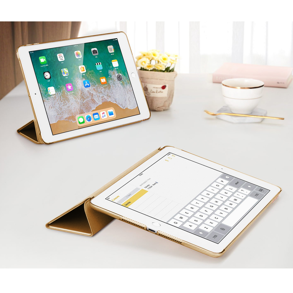 Zwei goldene iPads auf einem weißen Tisch, eines im Standmodus, das andere mit einer Tastatur.