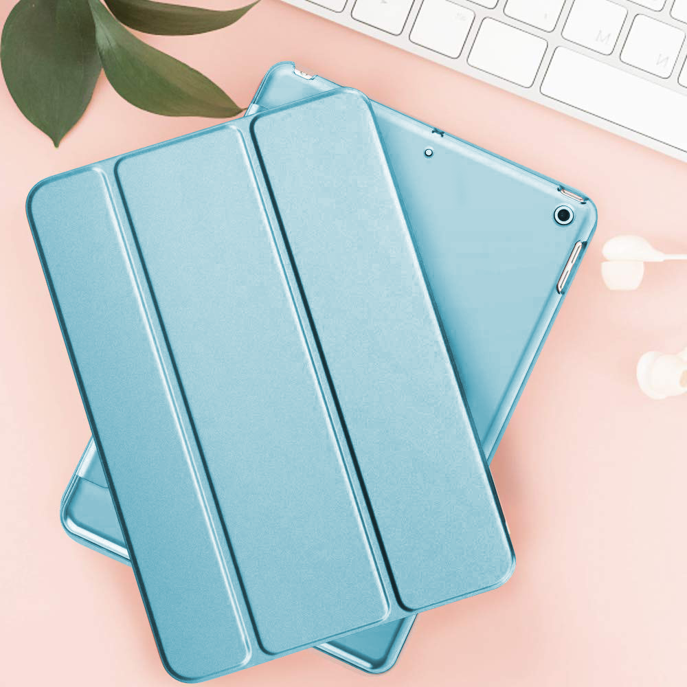Blaue Tablet-Hülle, geschlossen, auf rosa Oberfläche mit Tastatur und Blättern.