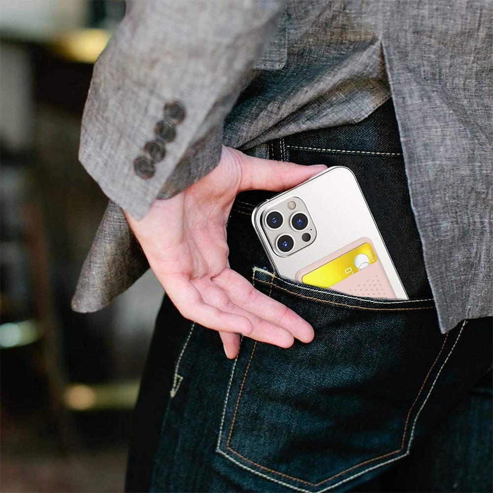 Ein Telefon mit Kartenhalter wird von einer Hand in eine Jeanshosentasche gesteckt.