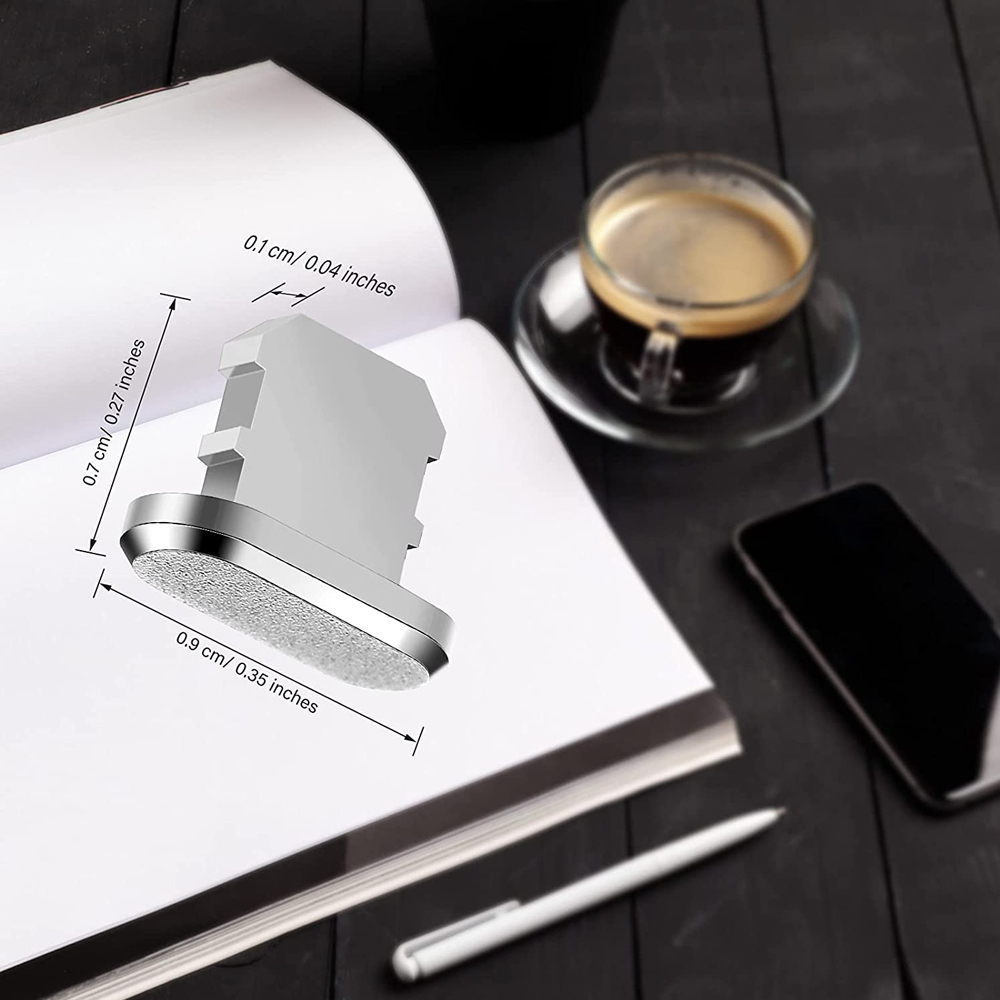Offenes Buch mit silbernem Knopf, Kaffeetasse, Telefon und Stift auf einer dunklen Holzoberfläche.