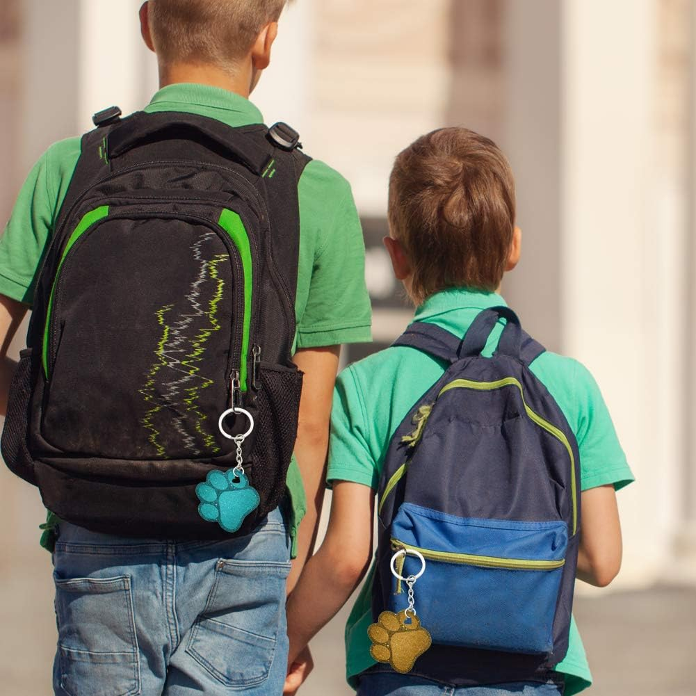 Zwei Jungen mit Rucksäcken, die Schlüsselanhänger mit Pfotenabdruck in Blau und Gold zeigen.