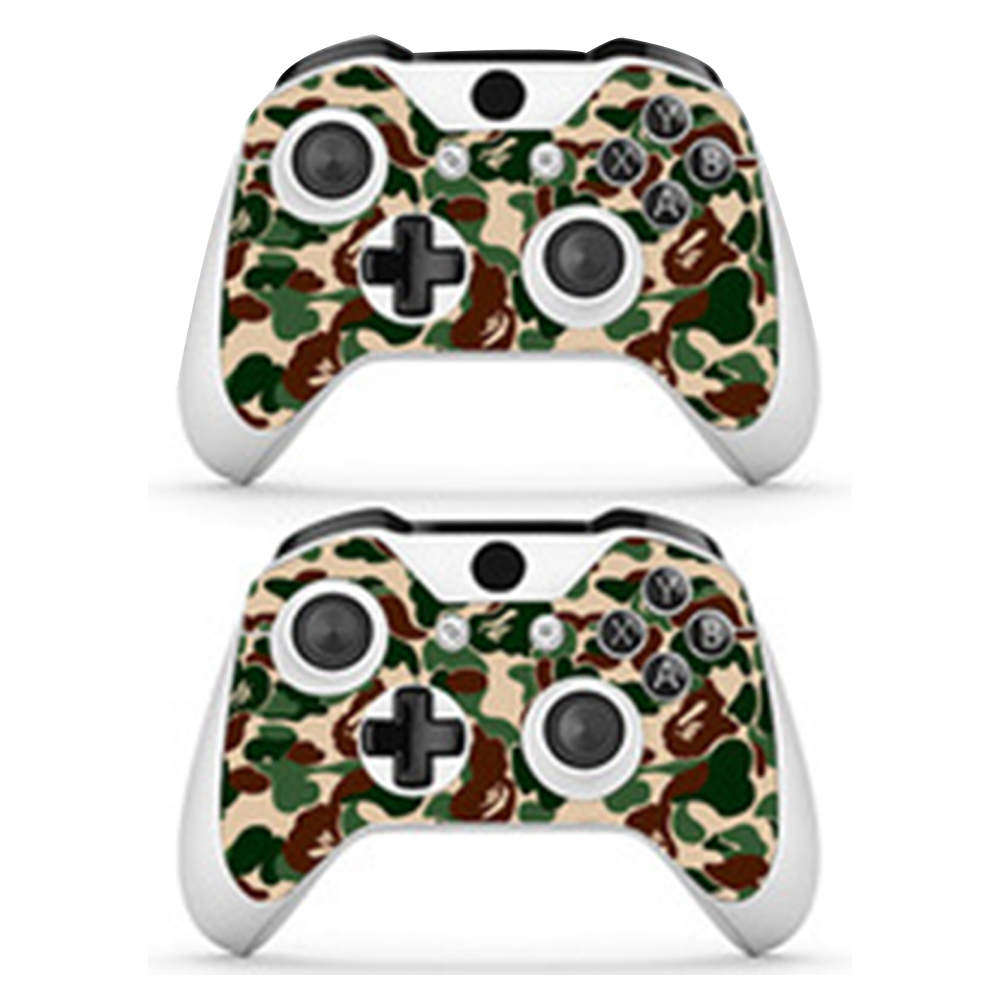 Es werden zwei getarnte Xbox-Controller gezeigt. Die Controller sind weiß mit einem Tarnmuster aus Grün, Braun und Beige.