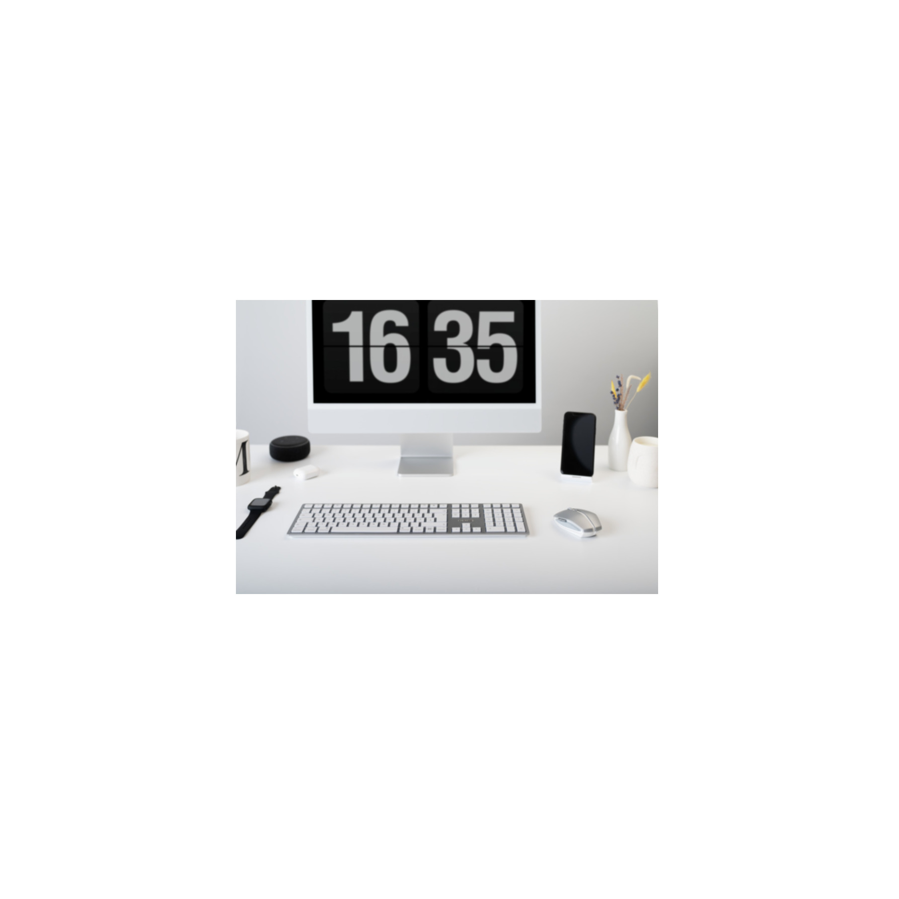 Een wit bureau met een computer, toetsenbord, muis, telefoon en accessoires.