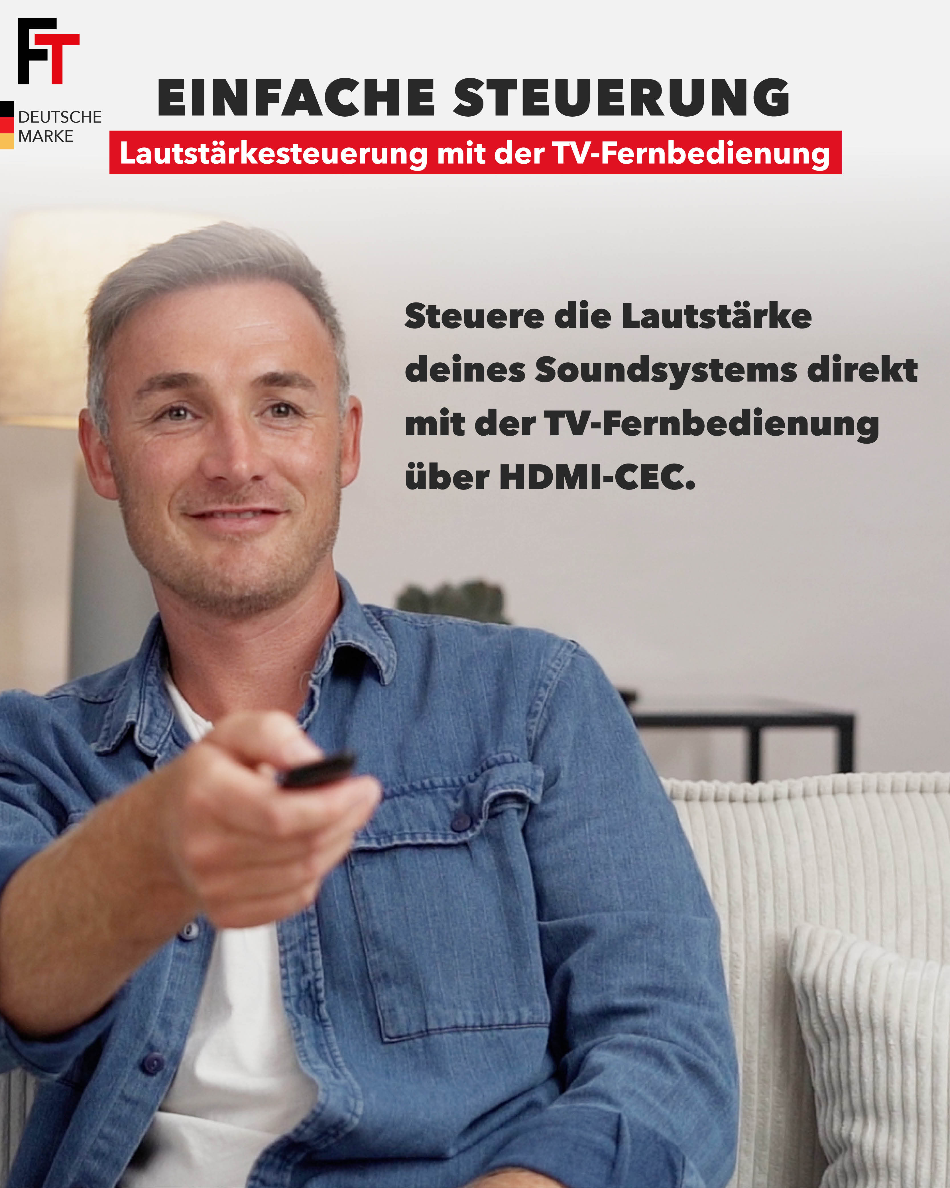 Mann auf einer Couch zeigt mit einer Fernbedienung und demonstriert die einfache Steuerung der Lautstärke des Soundsystems.